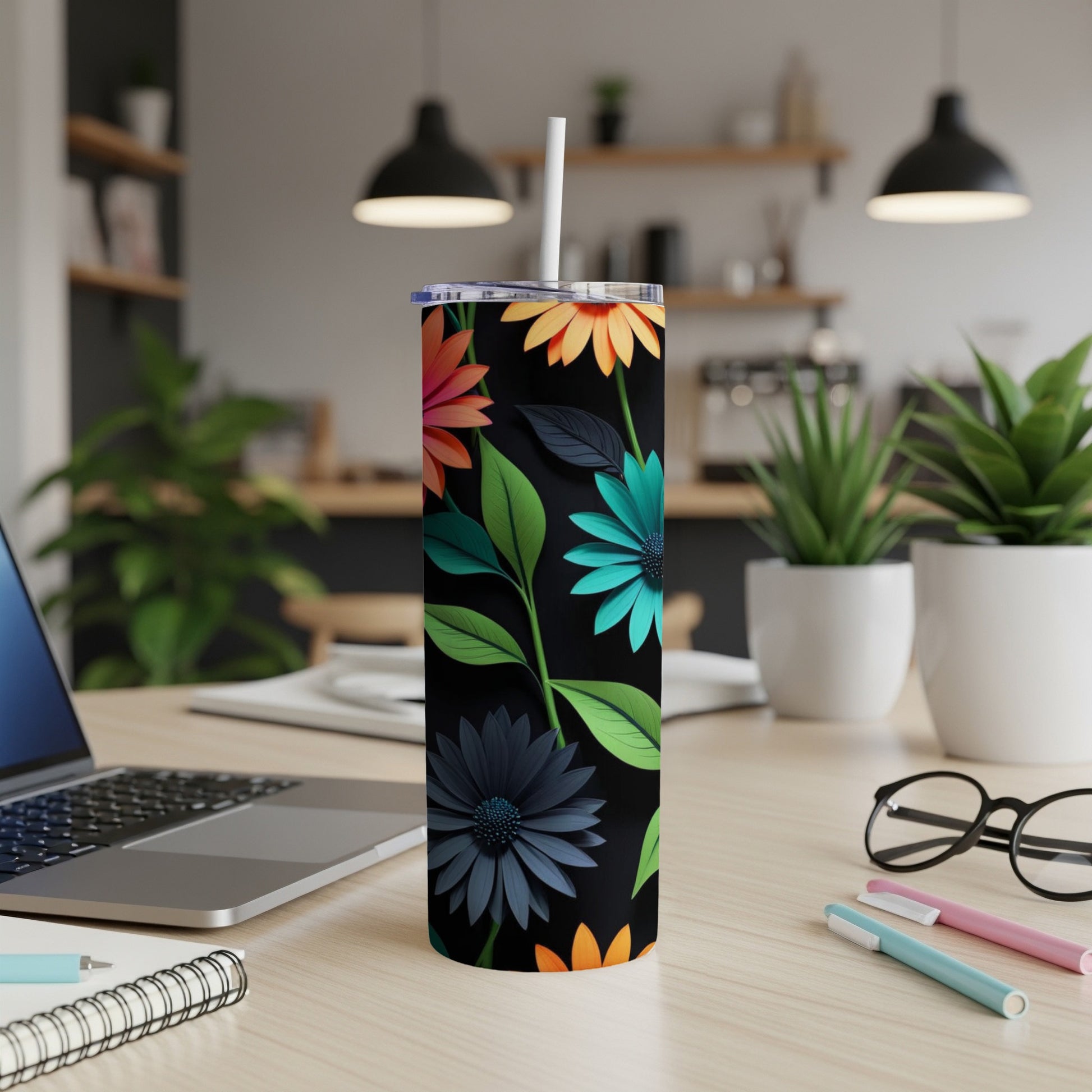 Tumbler with colorful floral pattern on black background, with straw.