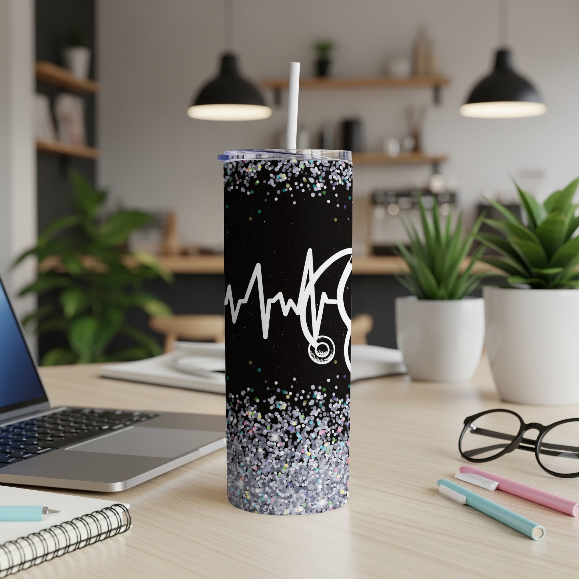 Black tumbler with stethoscope and heartbeat, glitter base, on a desk.