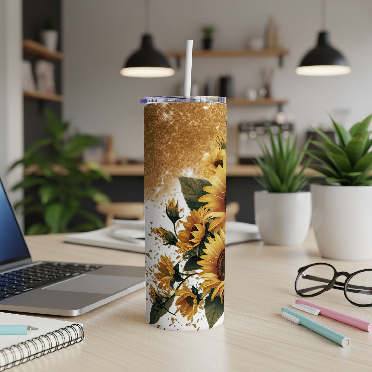 Glittery tumbler with sunflowers and white straw on a desk.