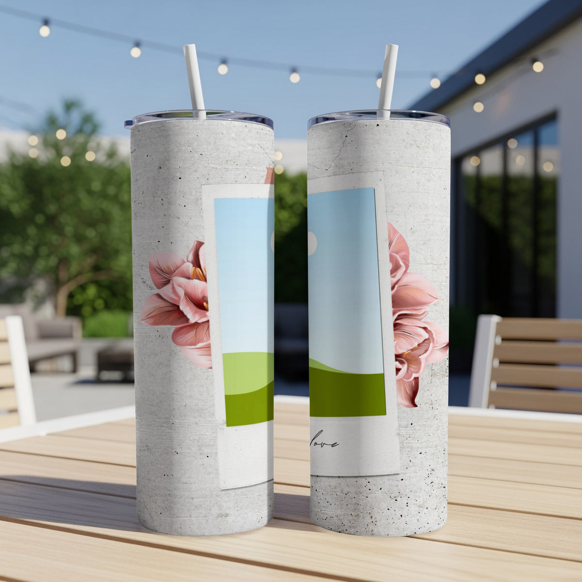 Two concrete textured tumblers with floral accents and straw on a table.