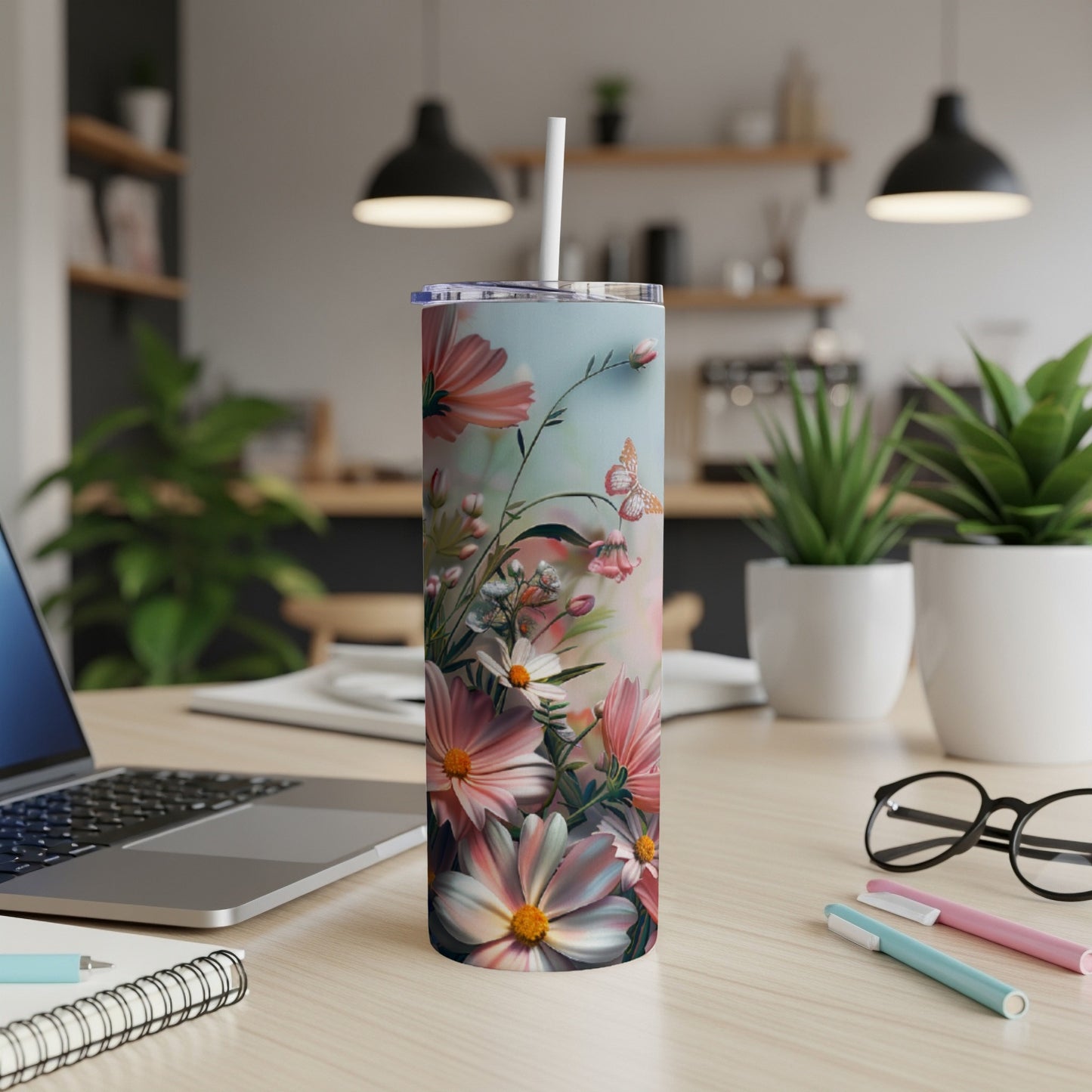 Floral tumbler with pink and white flowers and a butterfly on a desk.