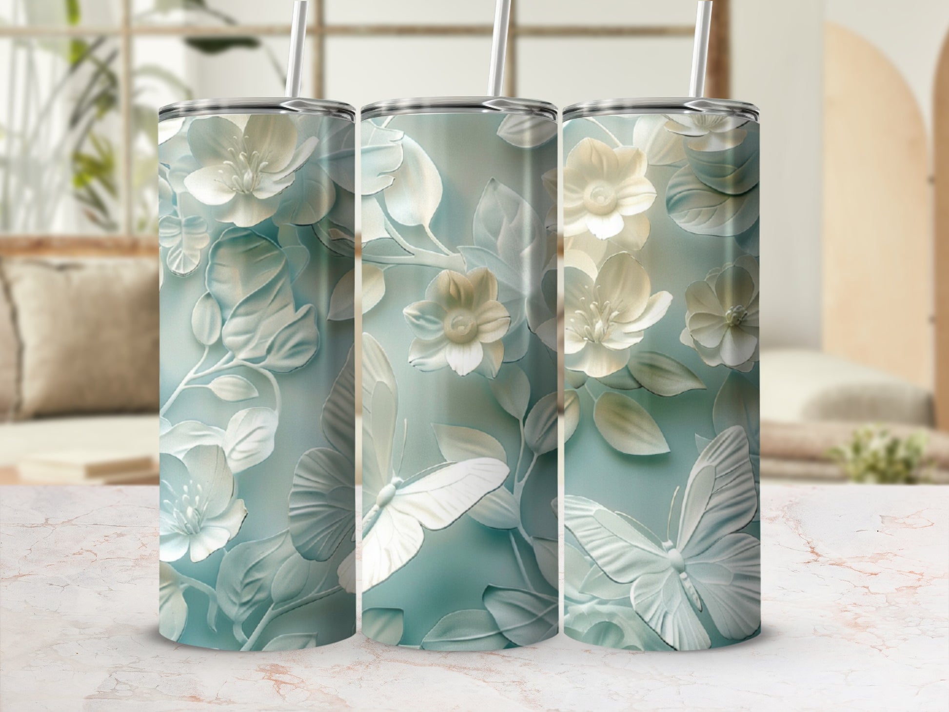 Three tumblers with a white floral and butterfly design on a light blue background.