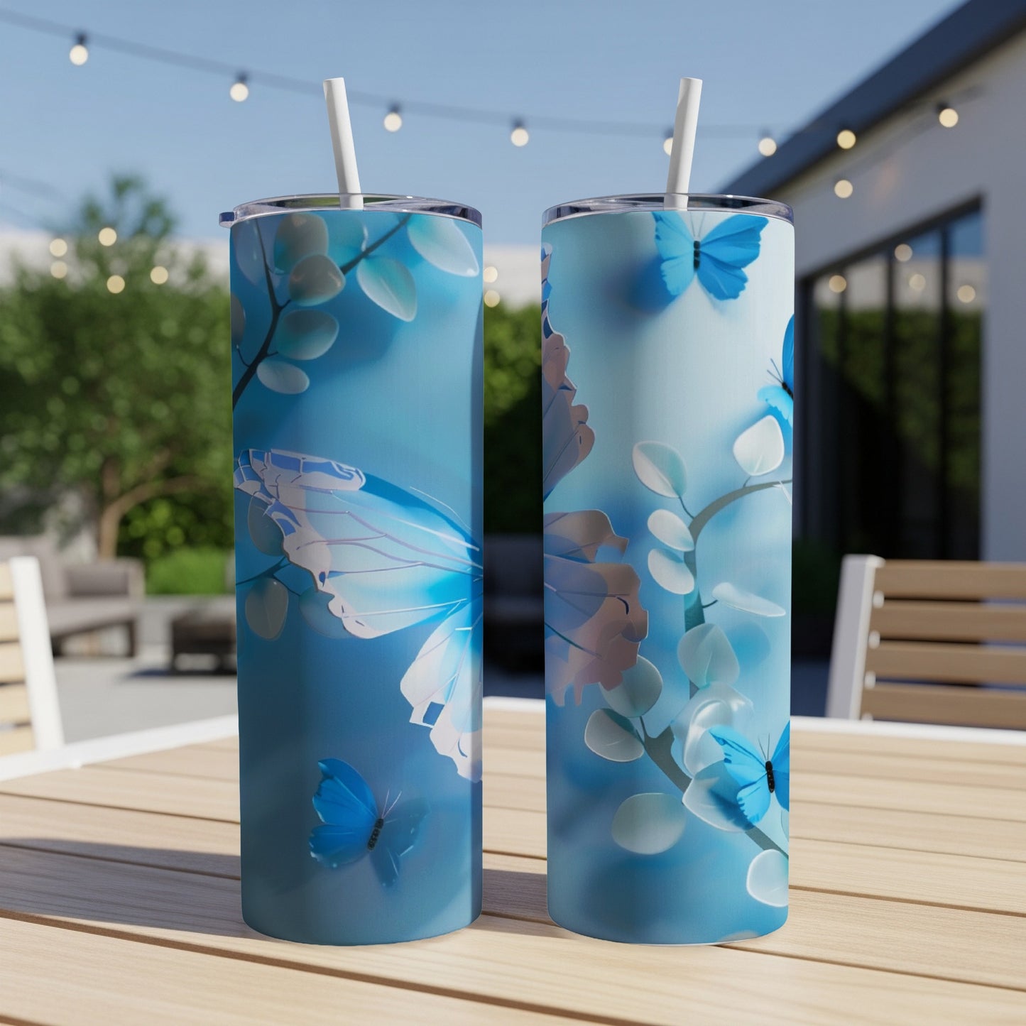 Two blue tumblers with butterfly and floral design on outdoor table.