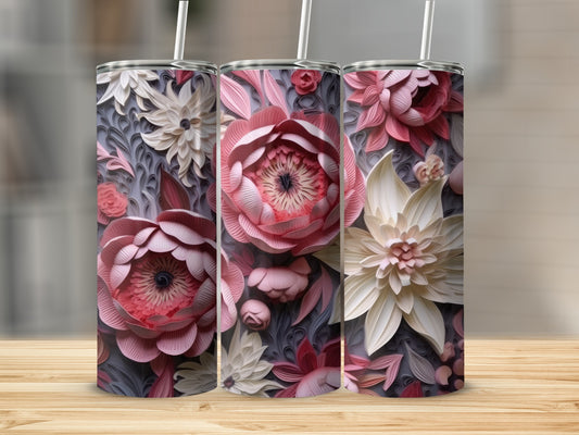 Three floral-patterned tumblers with straws on a wooden surface.