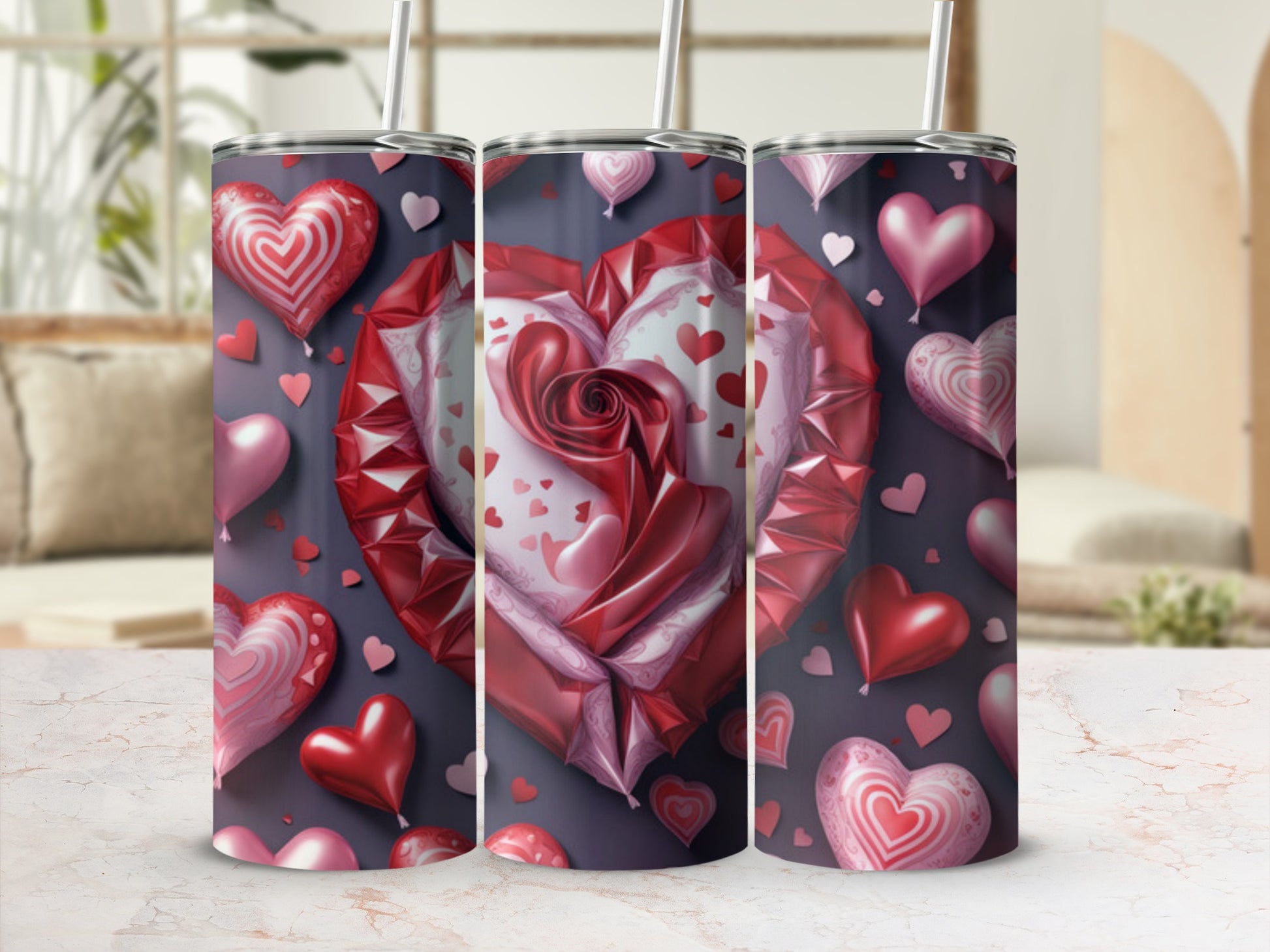 Three tumblers with red and pink heart designs and straws.