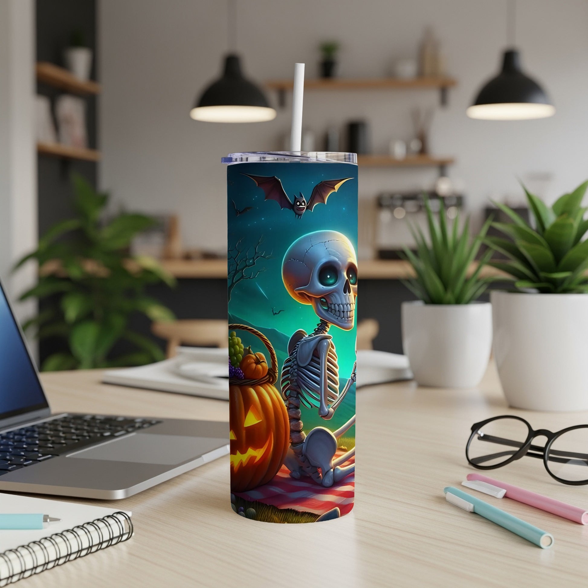 Halloween tumbler with skeleton, pumpkin, and bats on a picnic blanket.