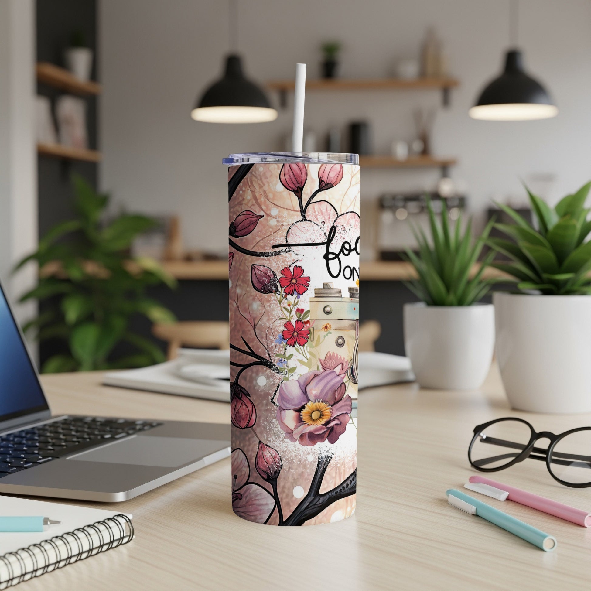 Floral tumbler with "Focus on" text, sitting on a wooden desk.
