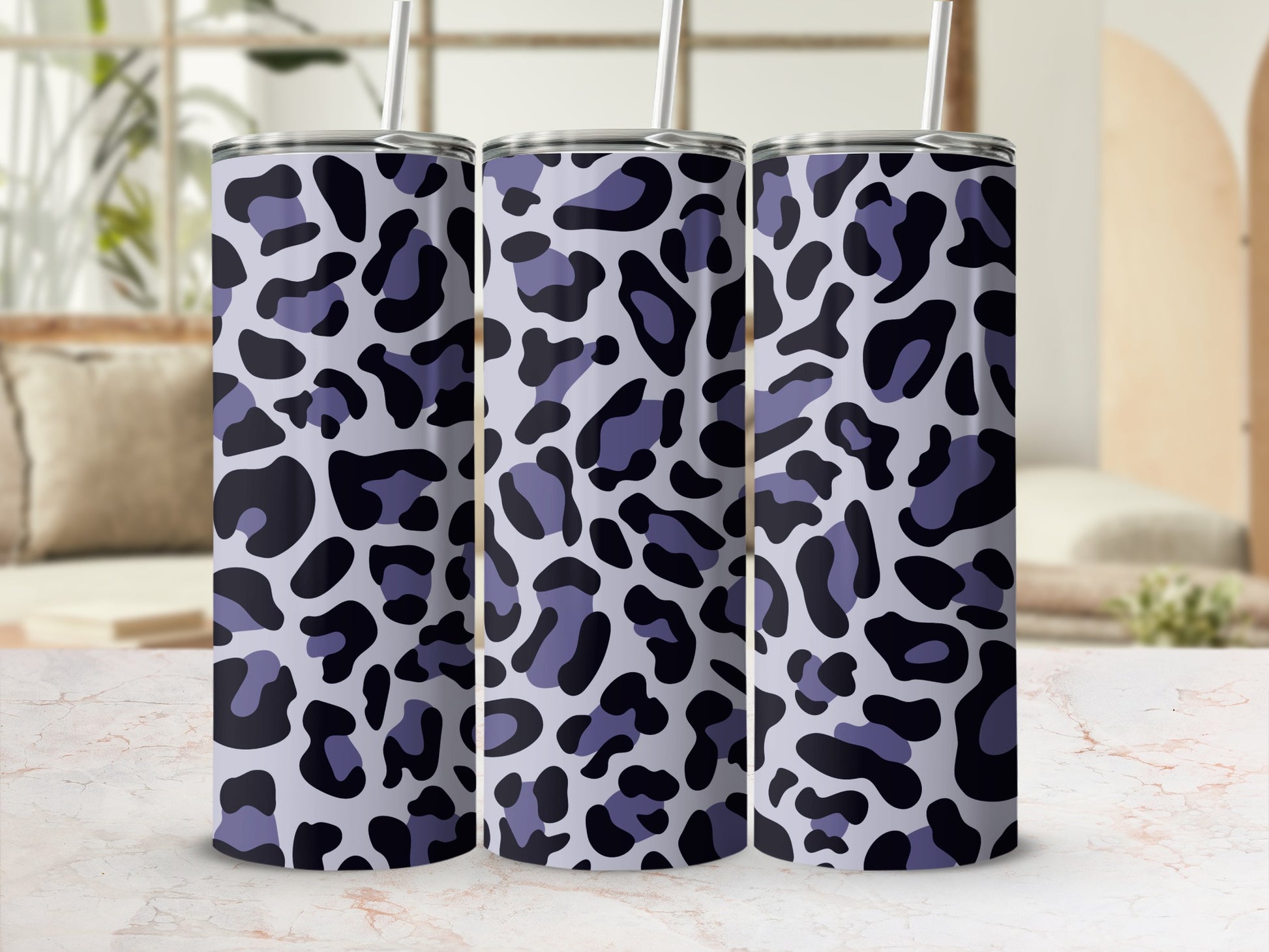 Three tumblers with a light purple and black leopard print pattern stand on a marble surface.