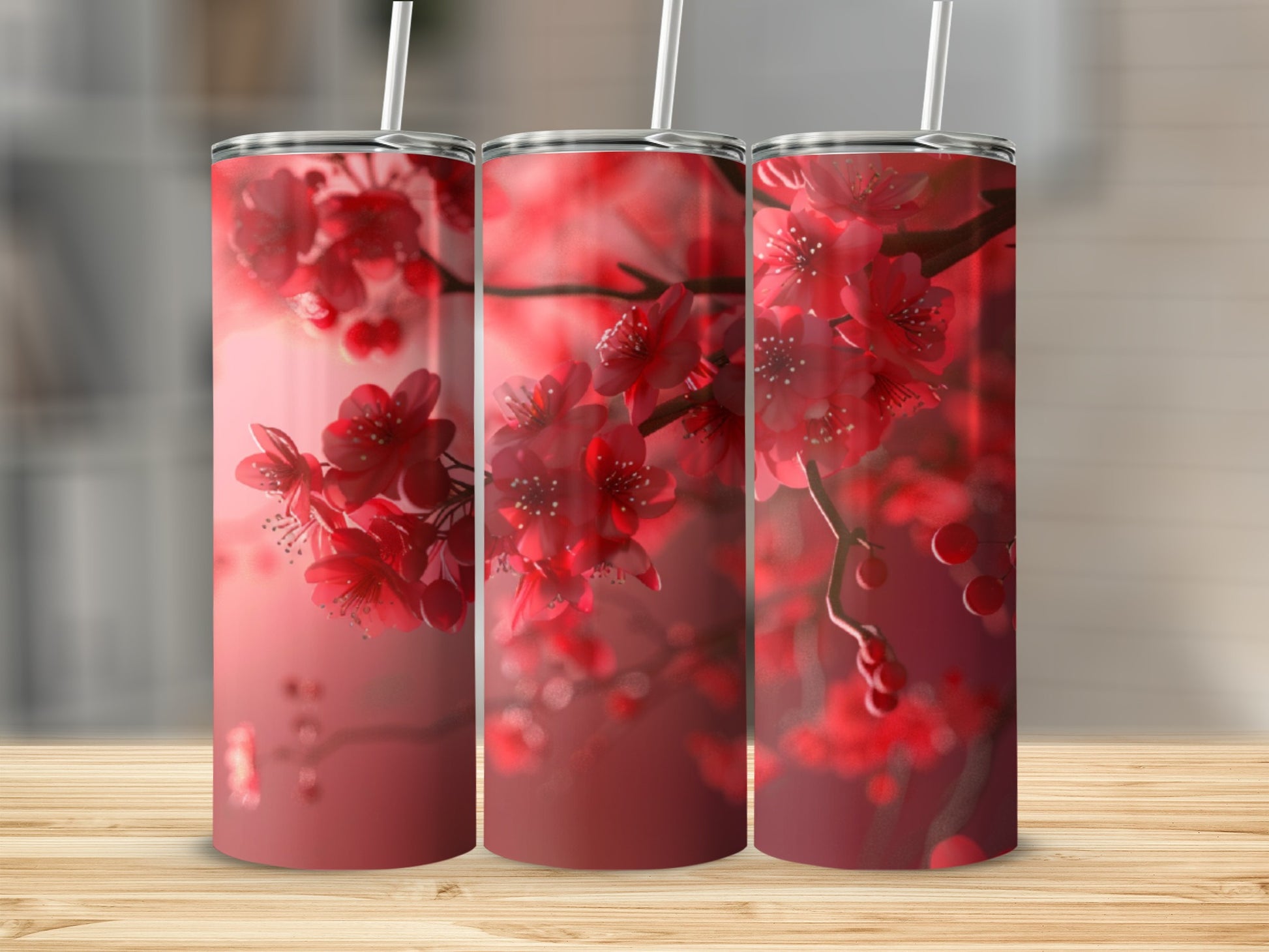 Three tumblers with red cherry blossoms on a wooden surface.