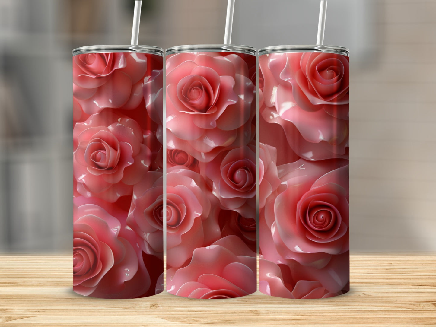 Three pink rose tumblers with straws on a wooden surface.