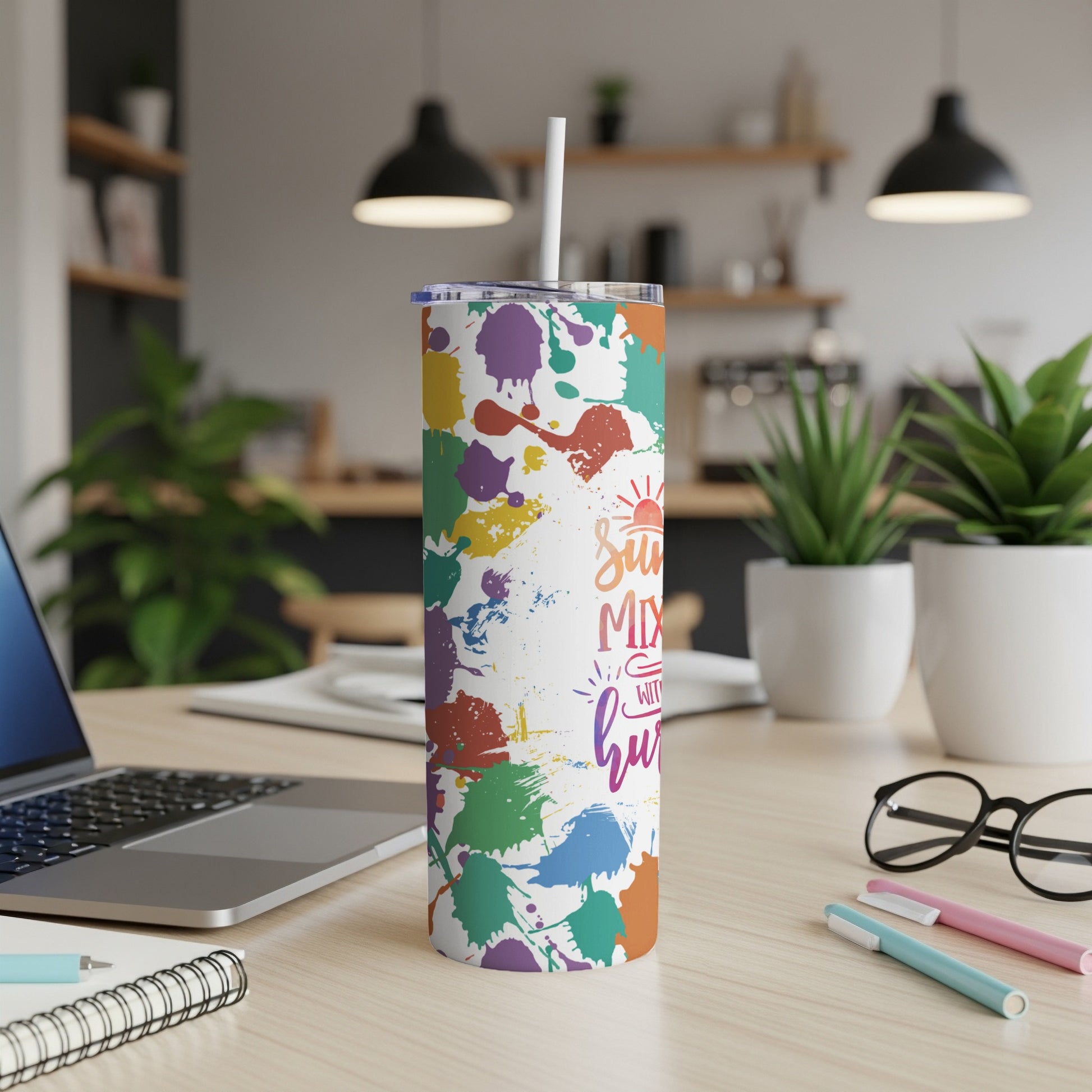 White tumbler with colorful paint splatters and text.
