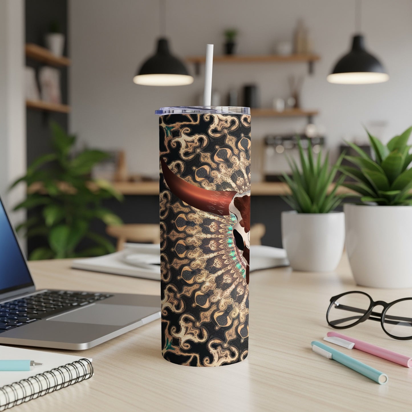 Skull and tribal pattern tumbler with straw on a desk.