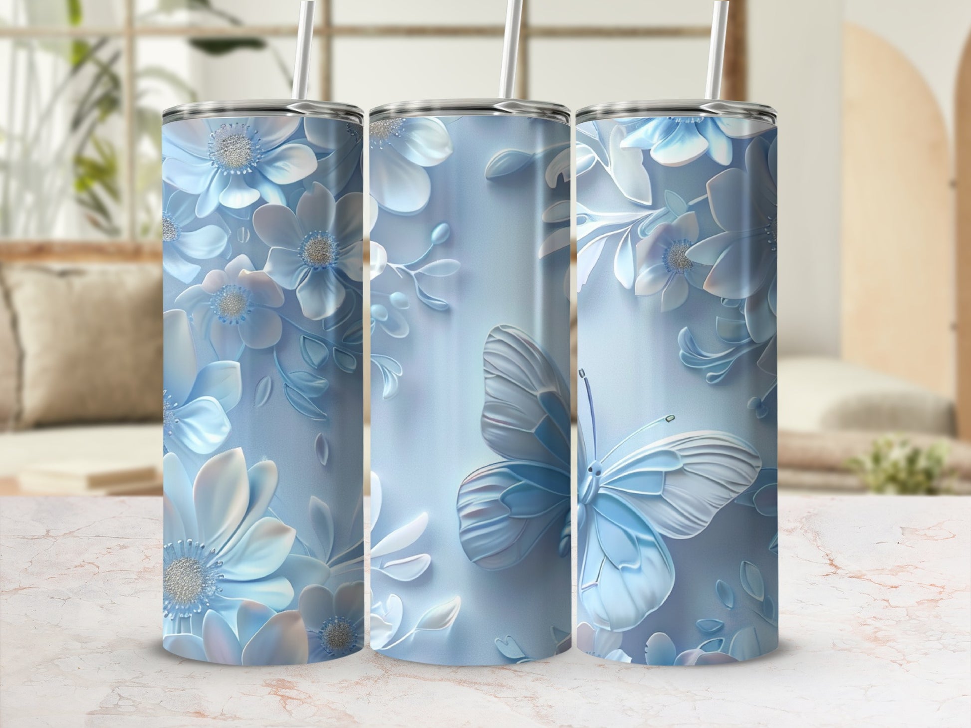 Three blue floral tumblers with butterflies and straws, on a patterned surface.