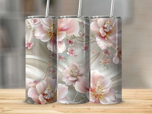 Three pink floral tumblers with straws on a wooden surface.