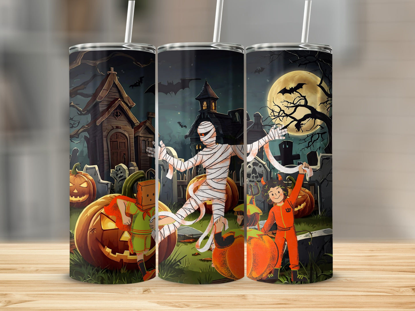 Halloween tumbler with pumpkins, mummy, and kids in costumes in a graveyard.