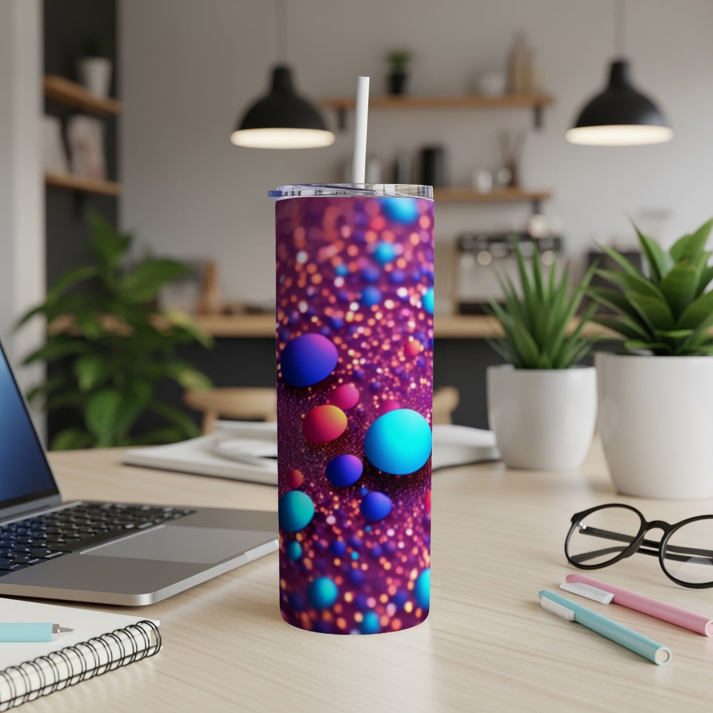 Tumbler with colorful bubbles and glitter design on a desk.