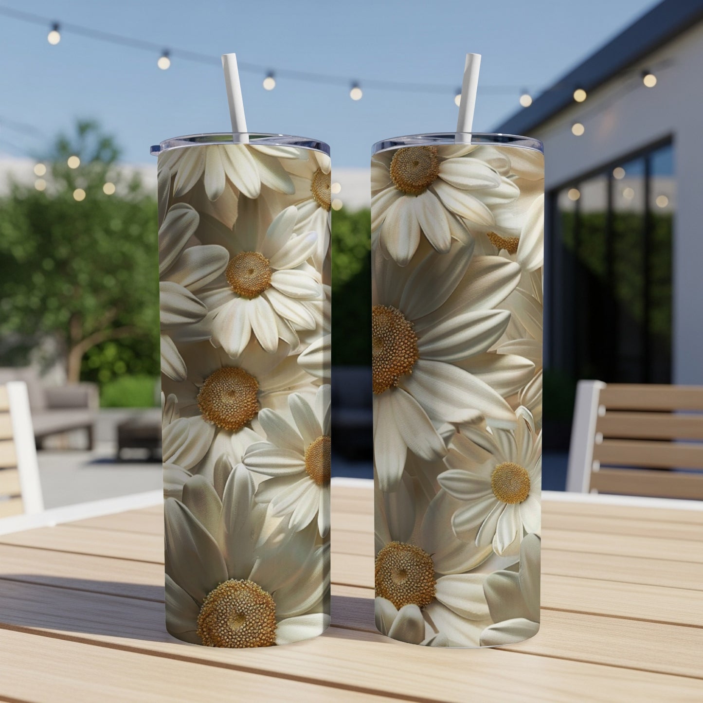 Two white daisy tumblers with straws on a wooden table outdoors.