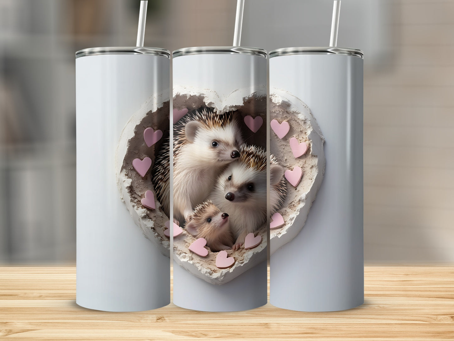 Three insulated tumblers, one featuring a heart with three hedgehogs inside.