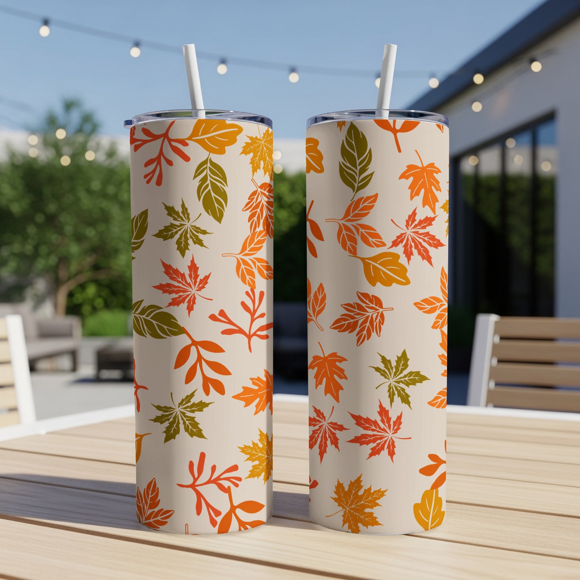 Two cream tumblers with autumn leaf pattern and white straws.