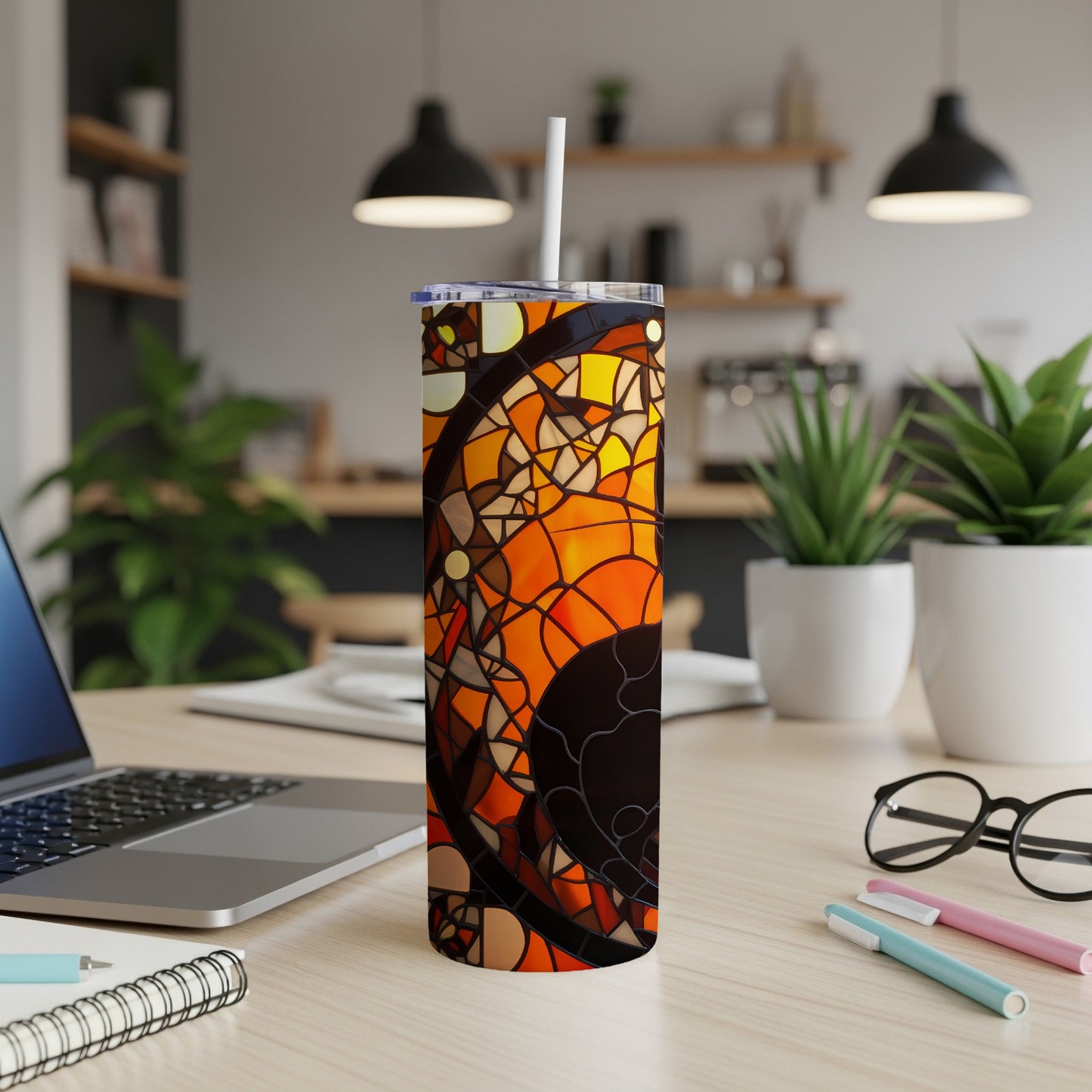 Tall tumbler with stained-glass-like orange and black geometric pattern, on a desk.