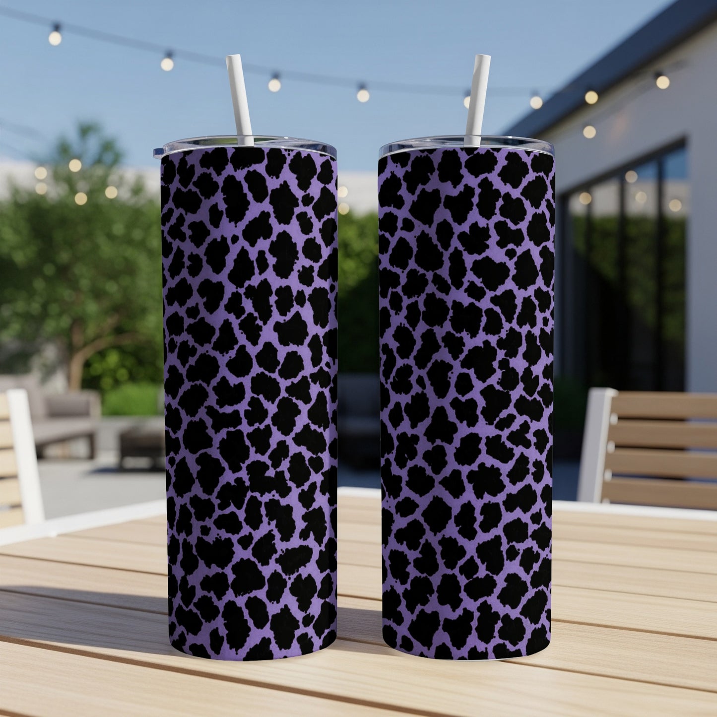 Two purple tumblers with black leopard print and white straws sit on a table.
