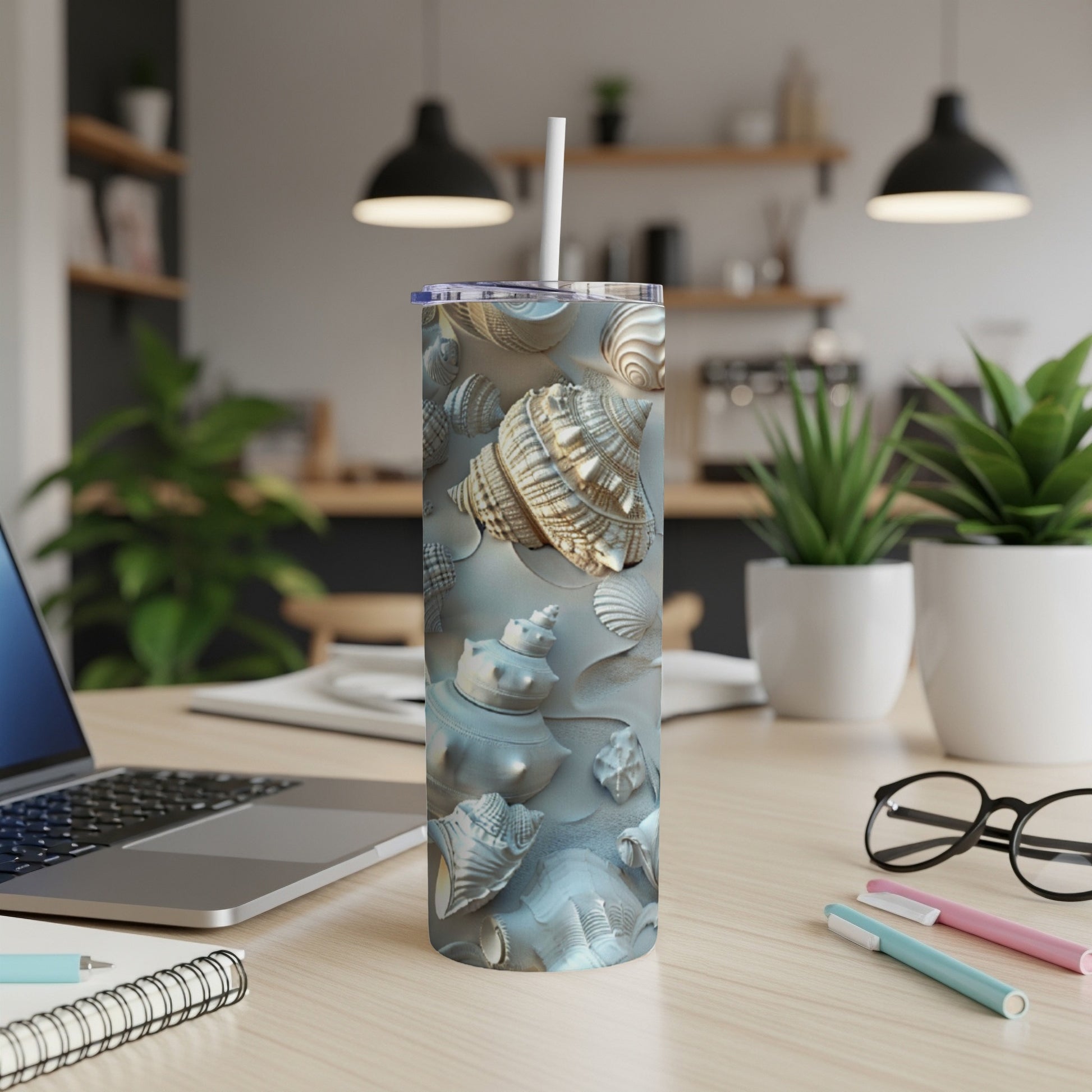 Beach-themed tumbler with various seashells and a straw on a desk.