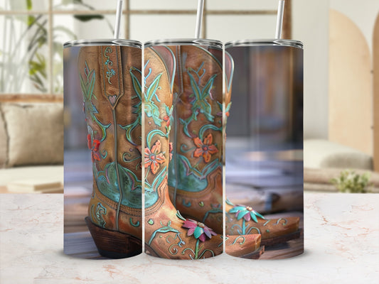 Three embroidered cowboy boots with floral designs and straws on a marble surface.
