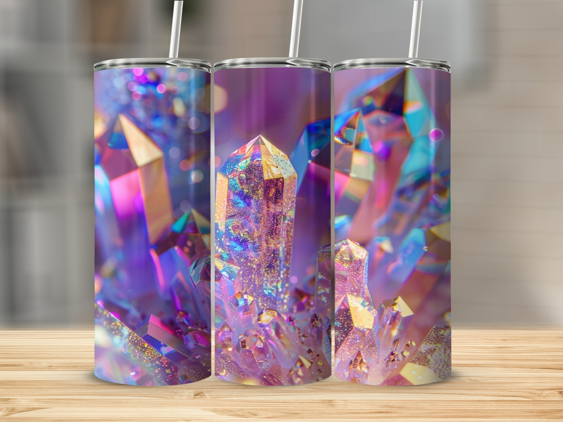 Three tumblers with iridescent crystal designs and straws on a wooden surface.