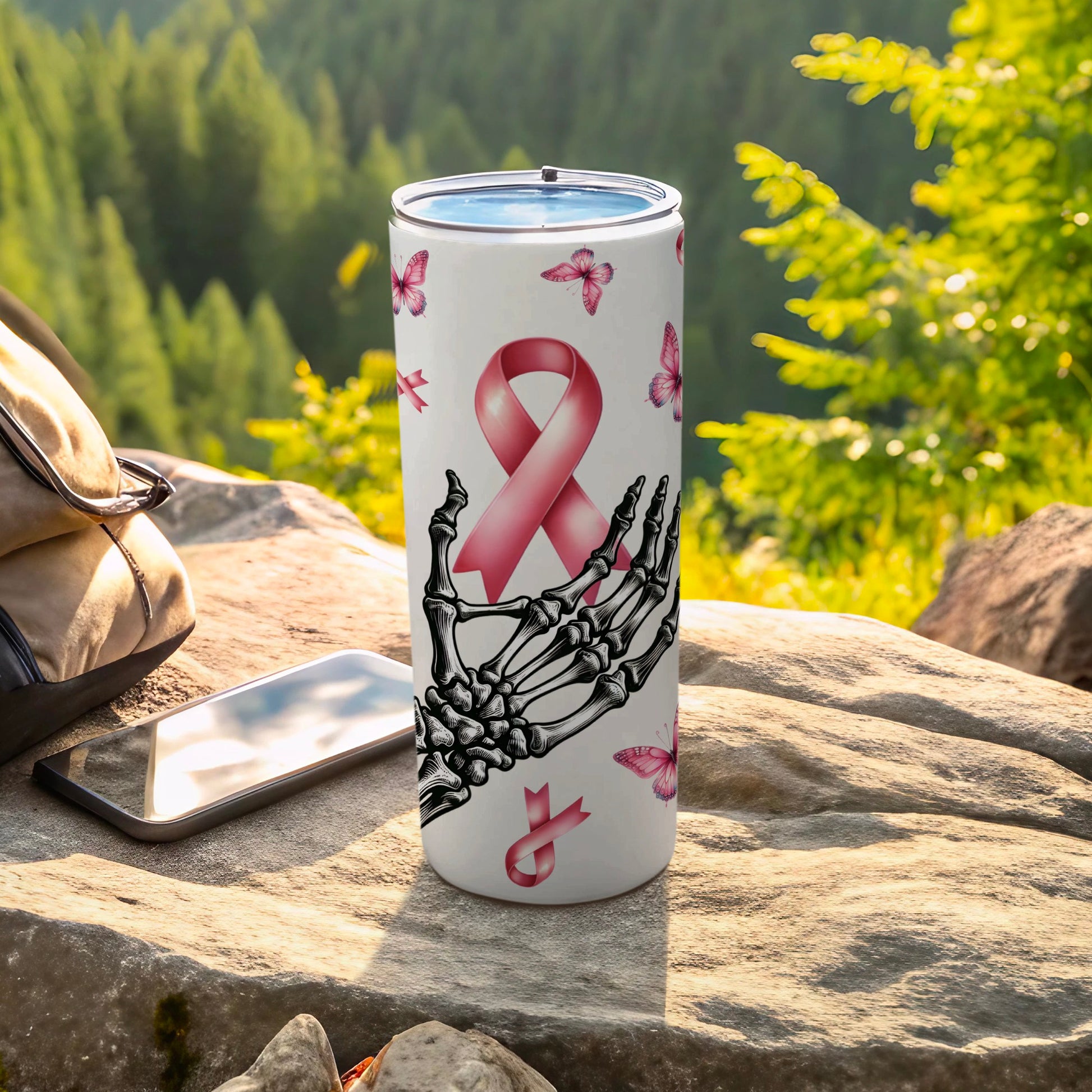 Skeleton hand holding a pink ribbon with butterflies on a white tumbler.