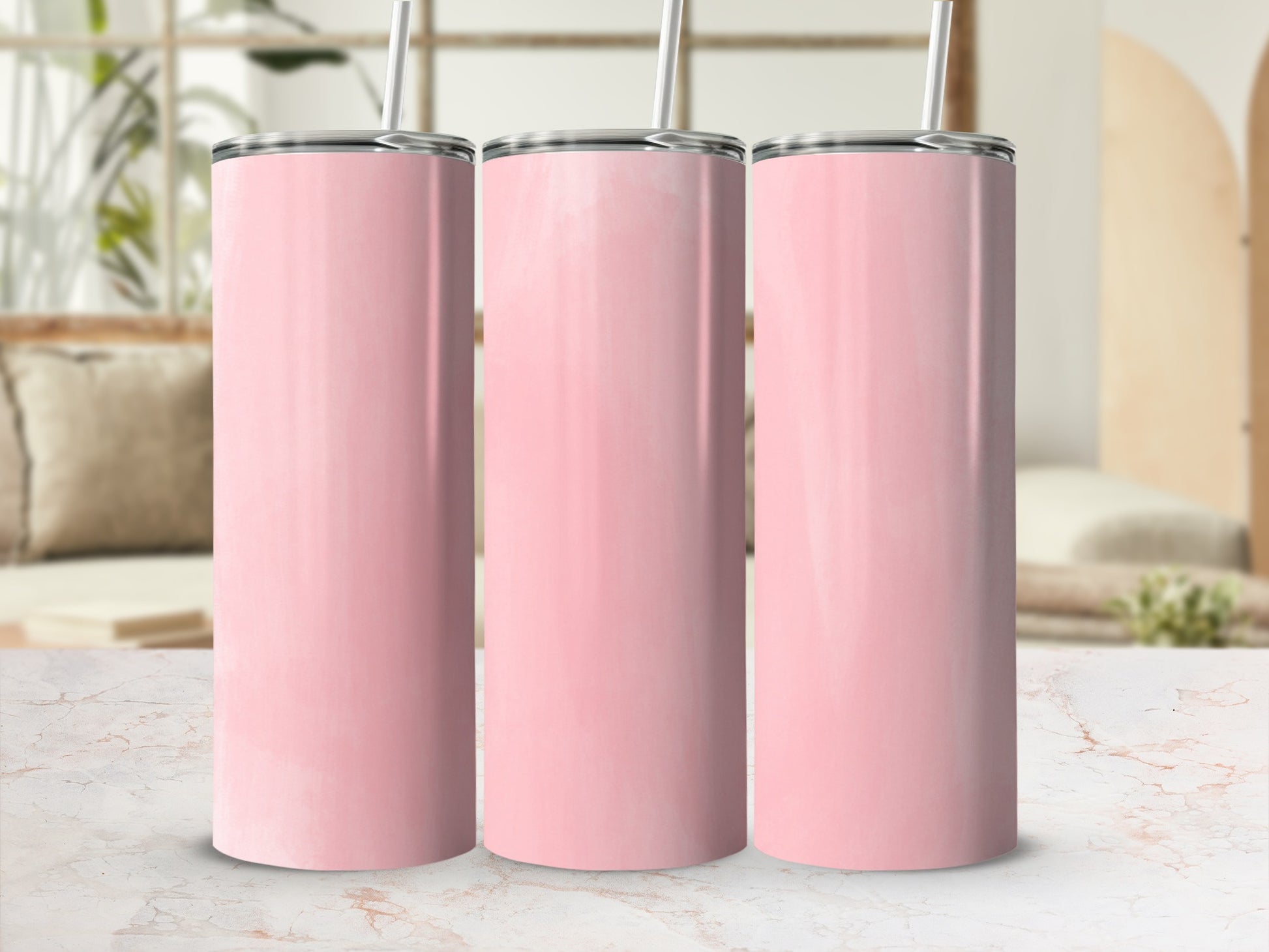 Three pink tumblers with straws stand on a marble countertop in a bright room.