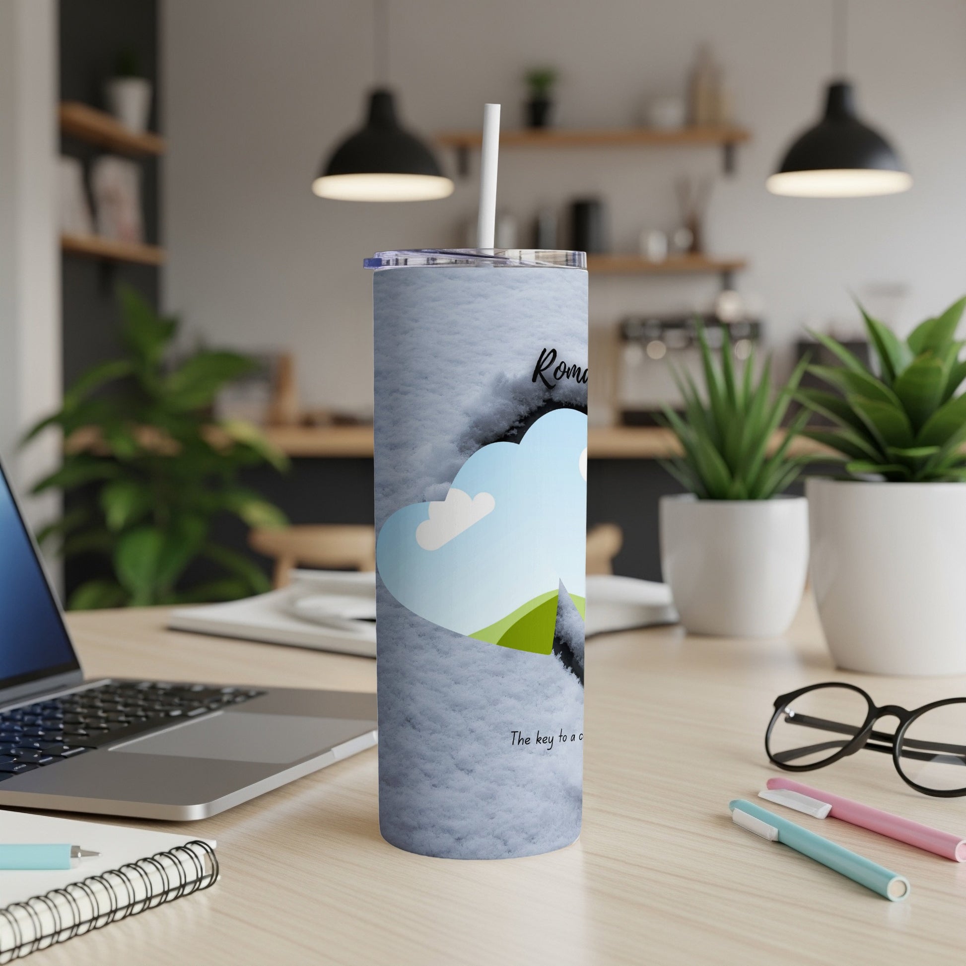 A white tumbler with a blue sky and green hill design and text.