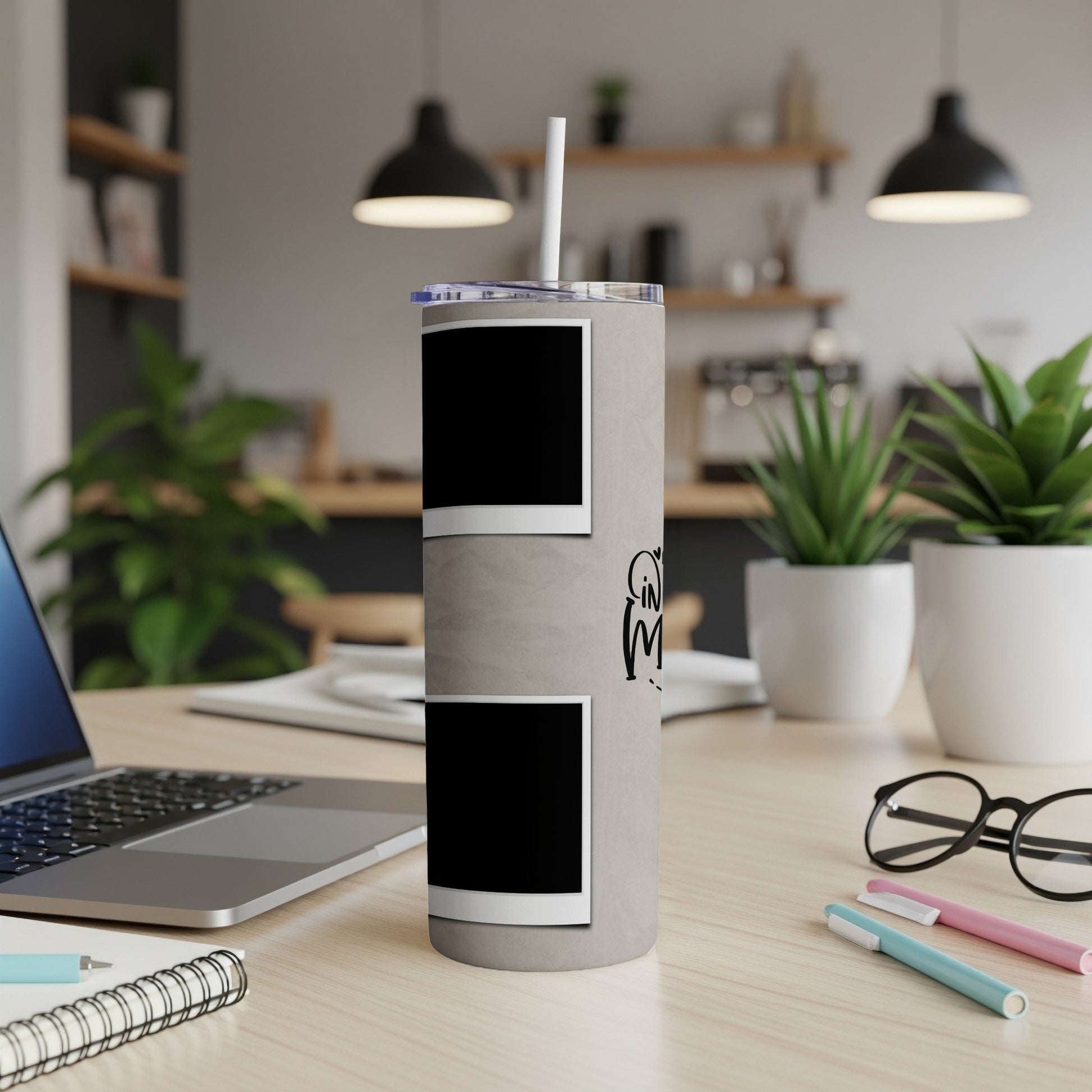 Gray tumbler with two photo frames and black text on a desk.