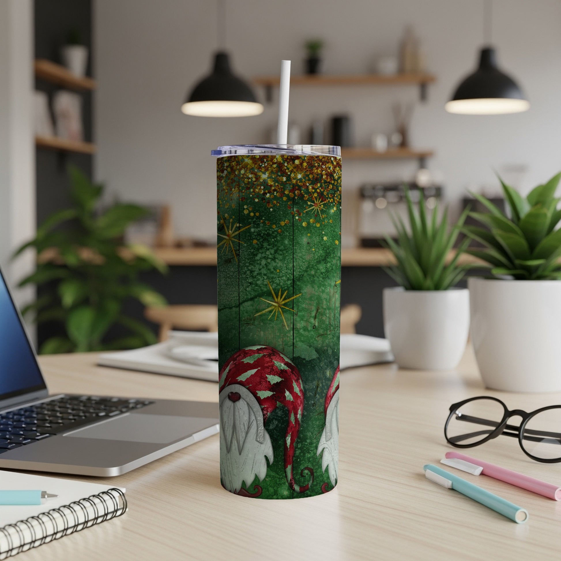 Green tumbler with glitter and two gnomes, placed on a desk.