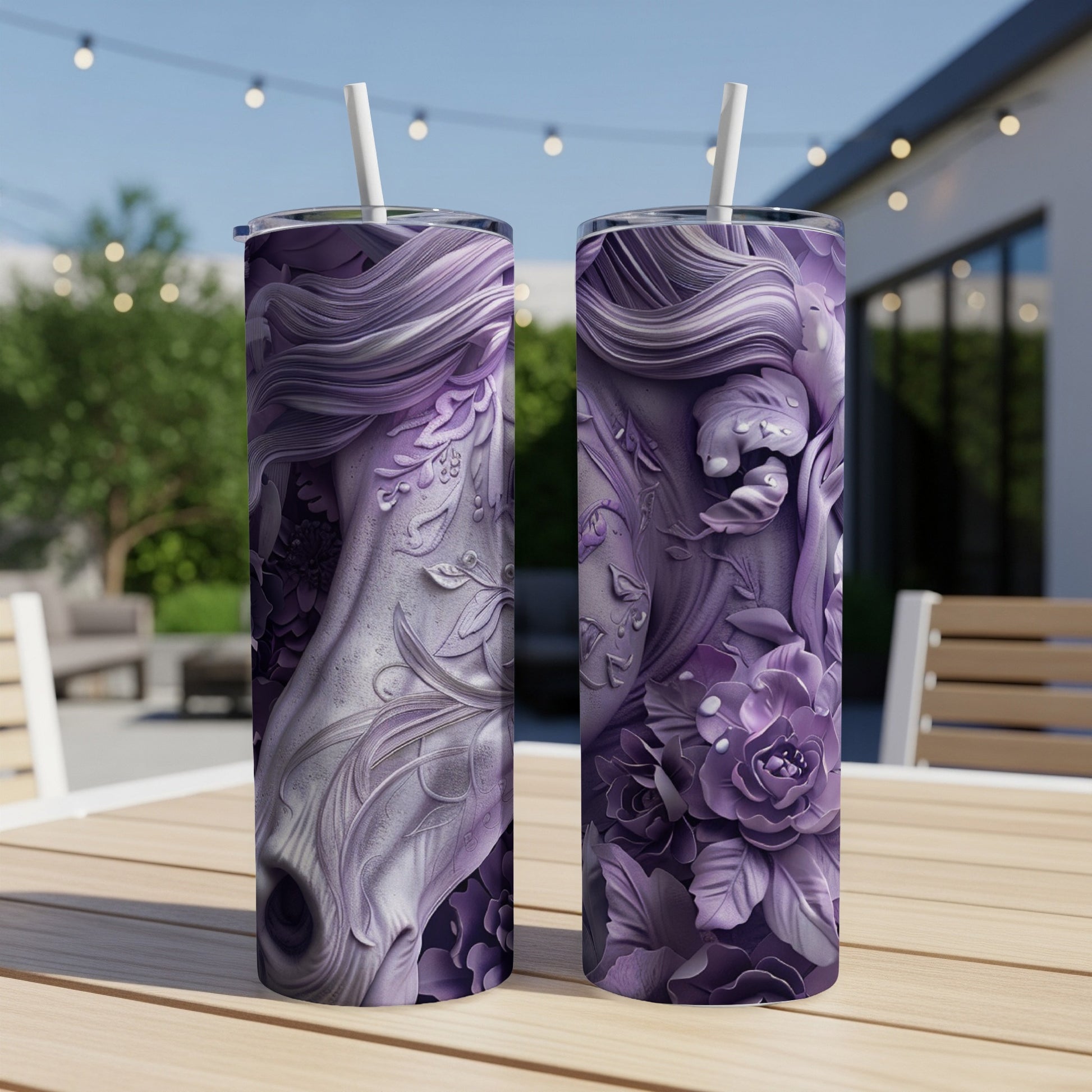 Two purple floral tumblers with straws on a wooden table outdoors.
