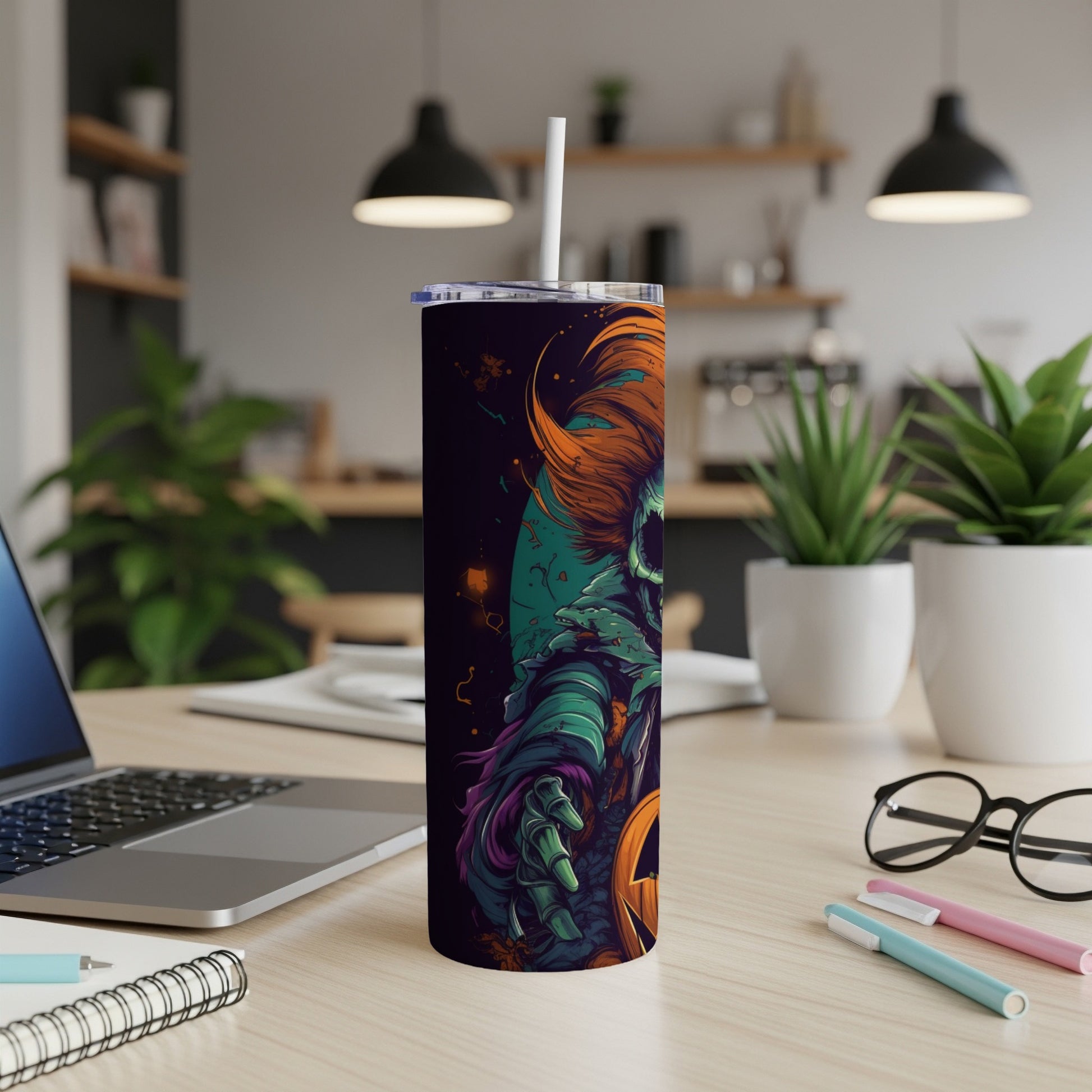 Tumbler with a scary clown and jack-o'-lantern design on a desk.