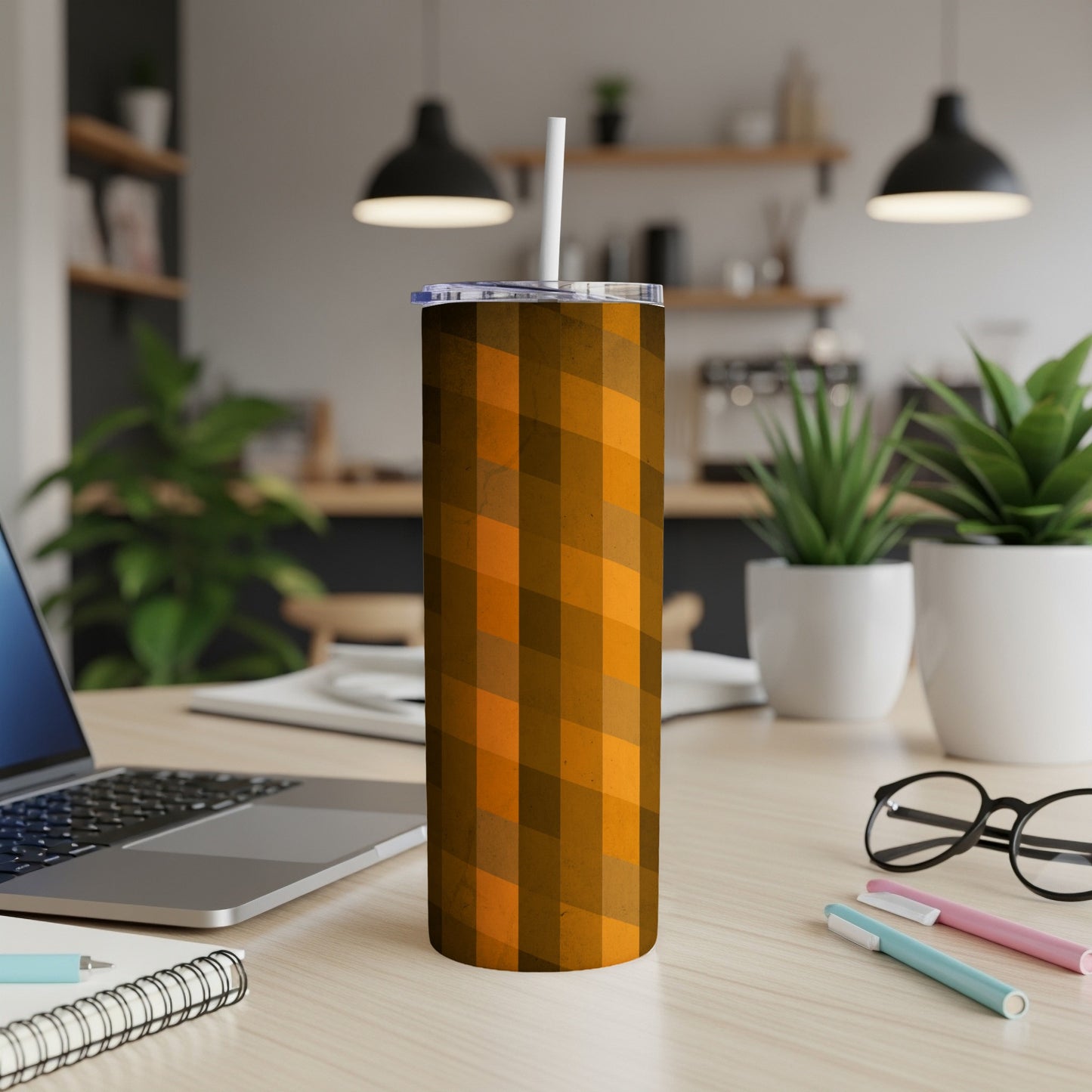 Orange geometric patterned tumbler with straw on a desk.