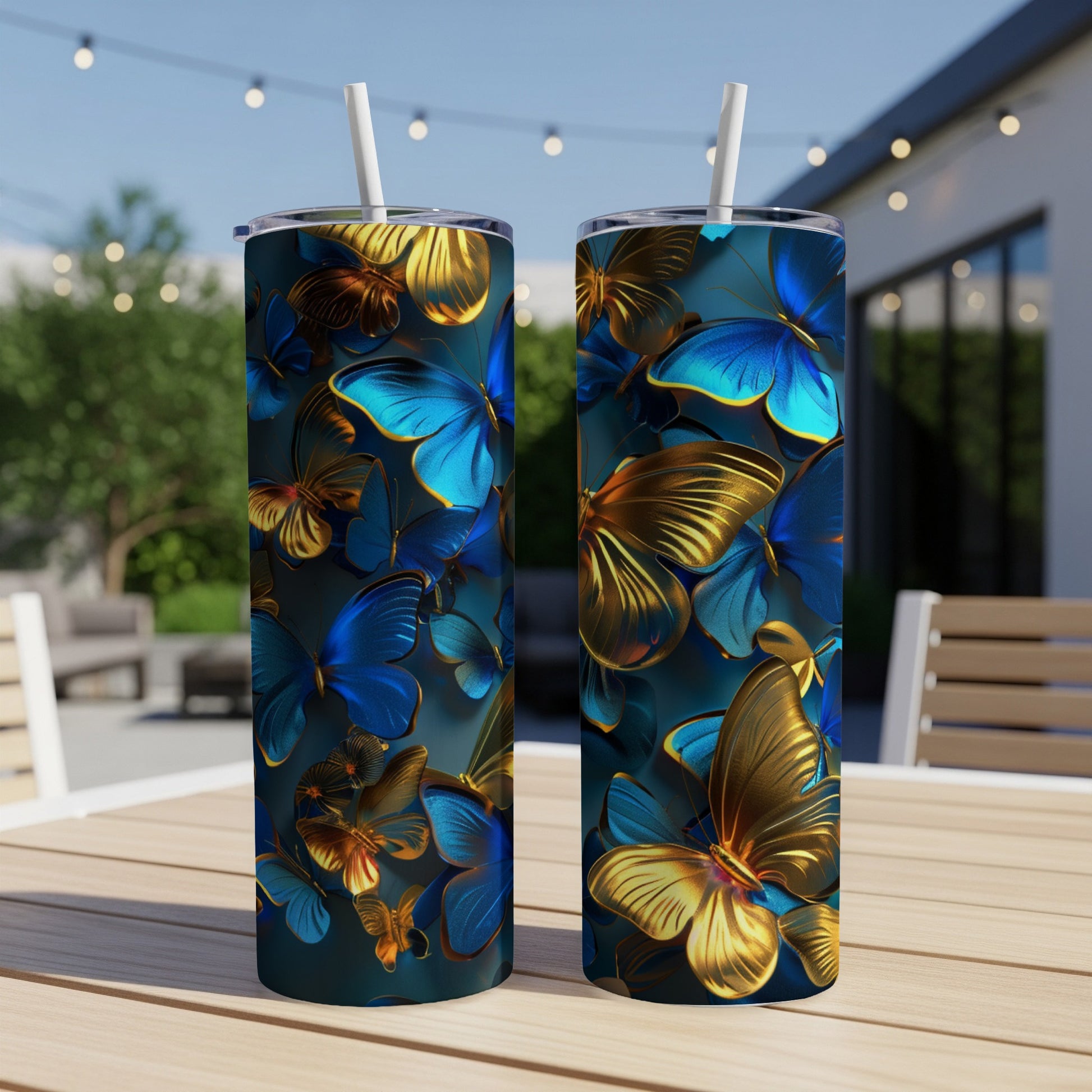 Two tumblers with a blue and gold butterfly pattern on a wooden table outdoors.