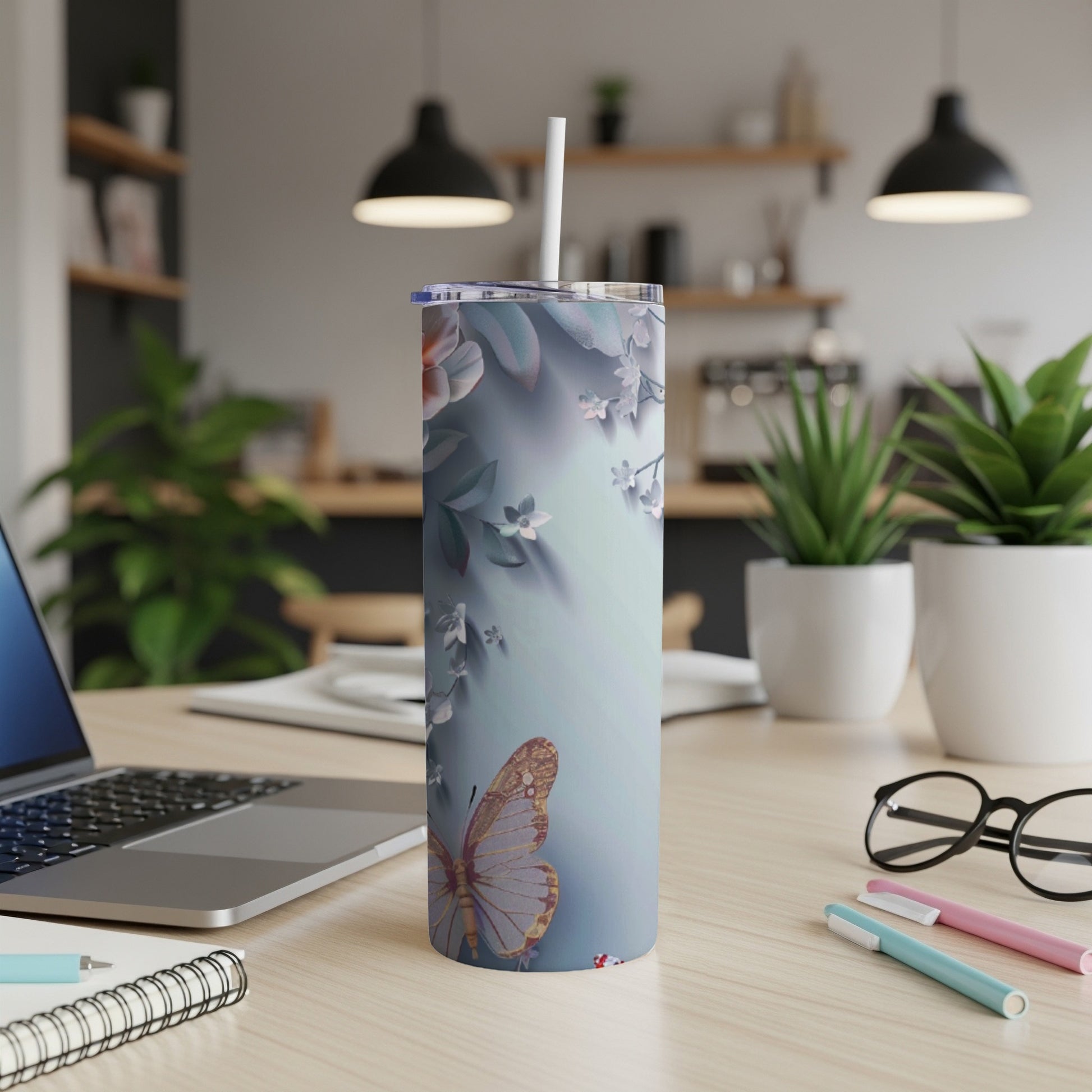 Tall tumbler with floral and butterfly design on a desk.