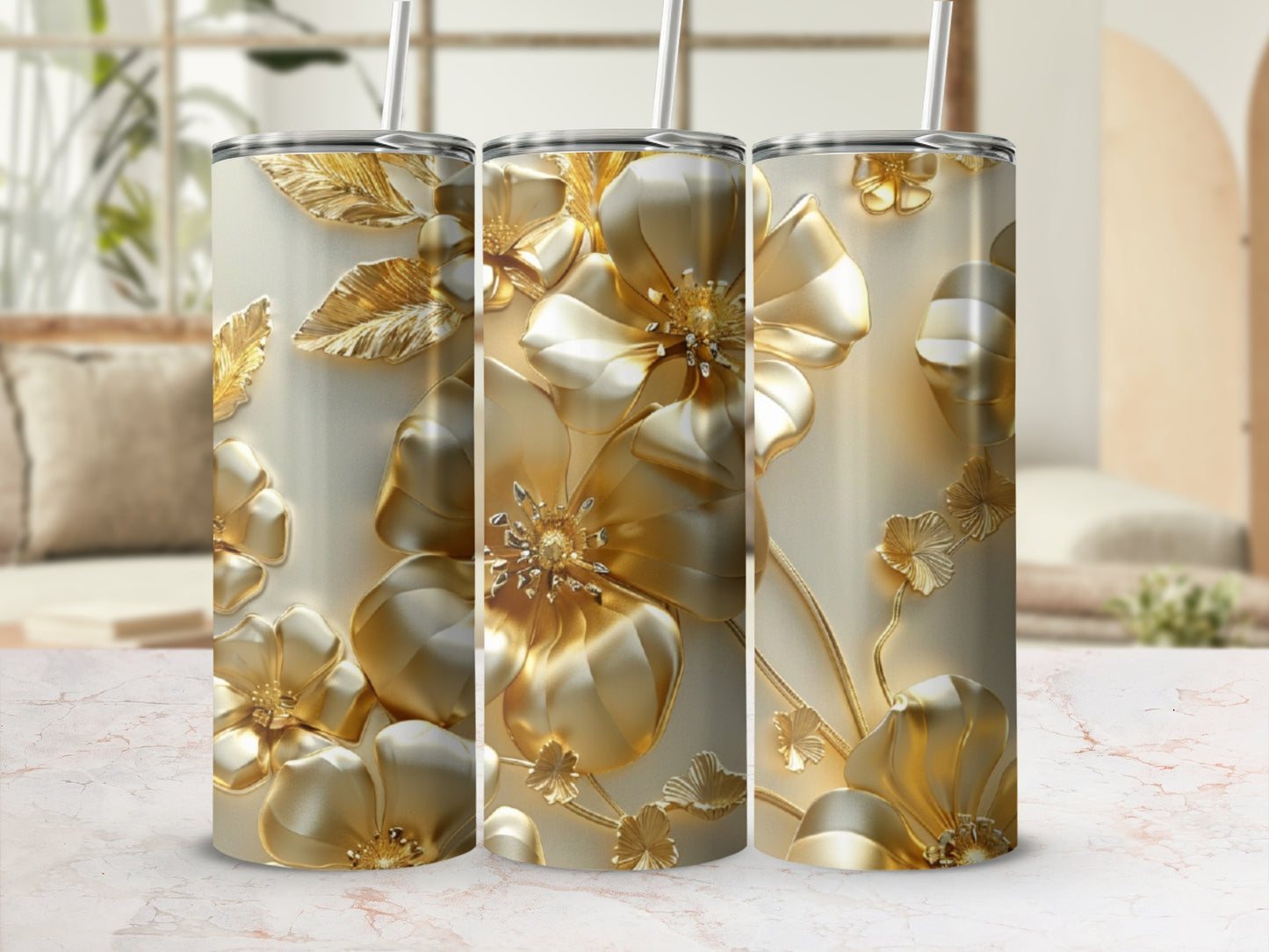 Gold floral embossed tumblers with straws against a blurred background.