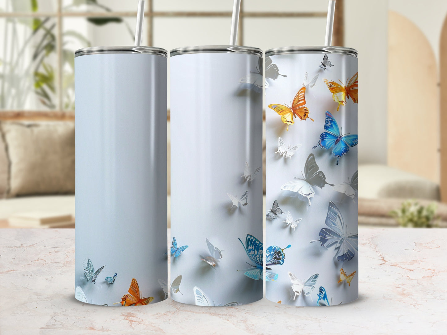 Three blank tumblers with butterfly designs on a marble surface.