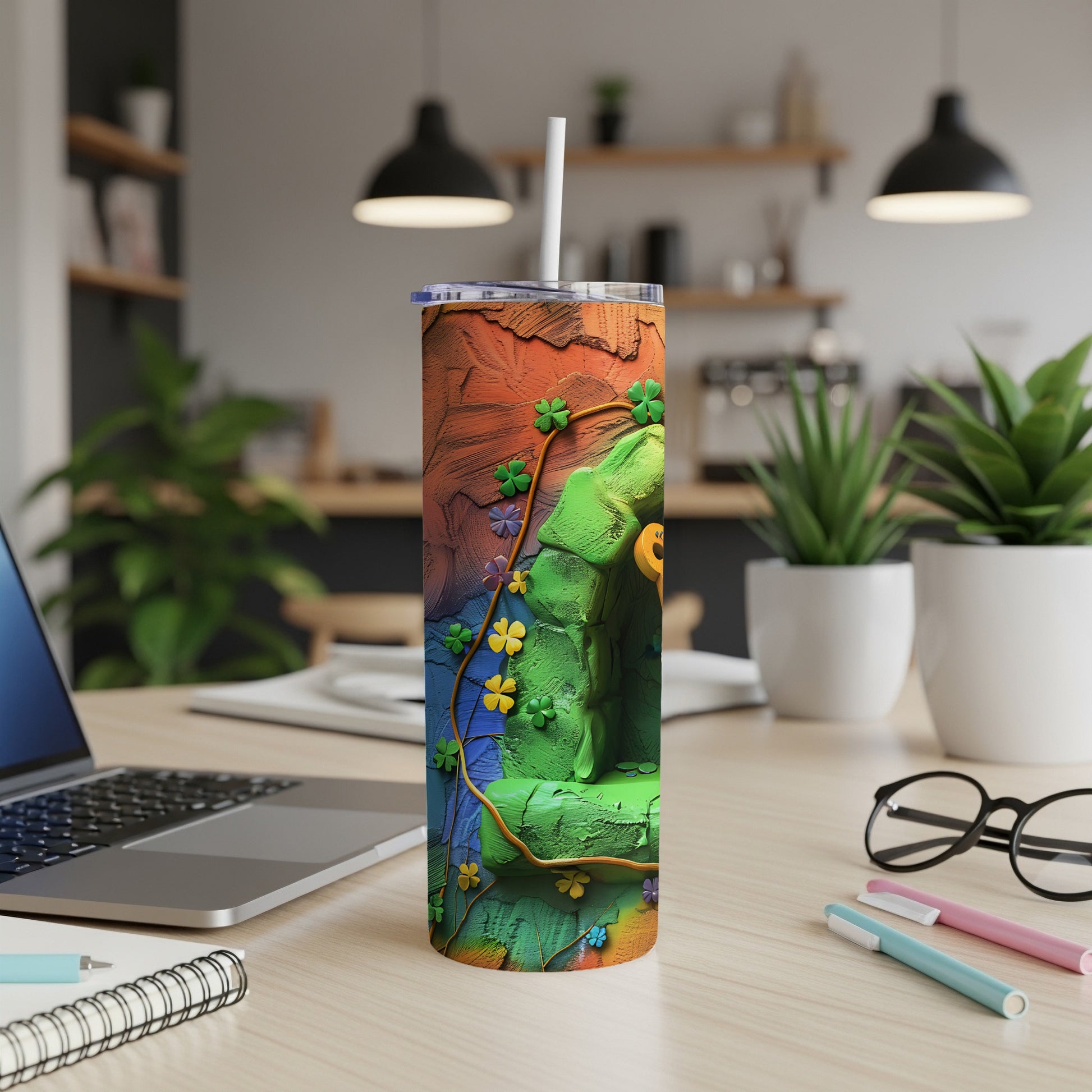 Green Buddha tumbler with floral vine design on a desk.