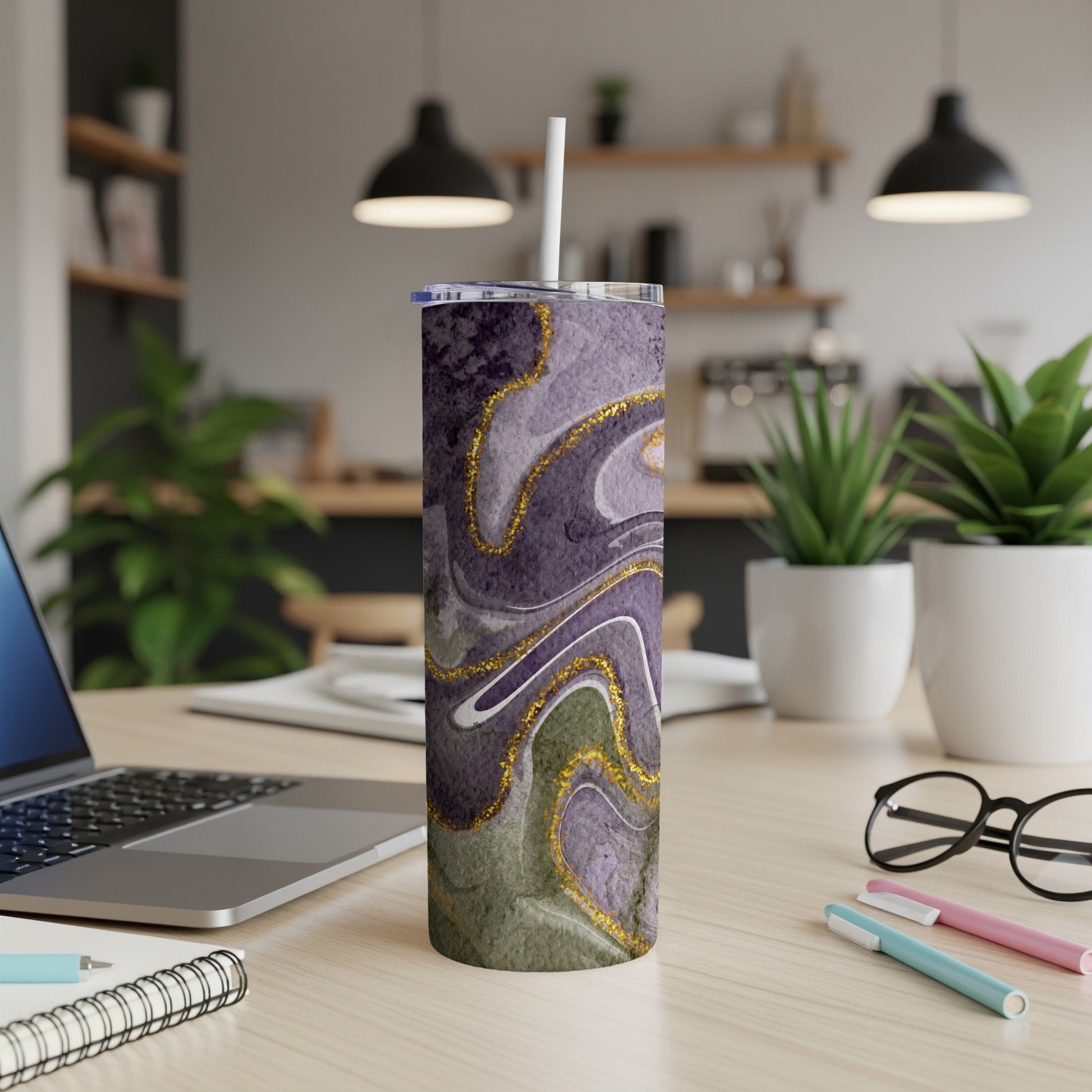 Purple and green marbled tumbler with gold accents, on a desk.