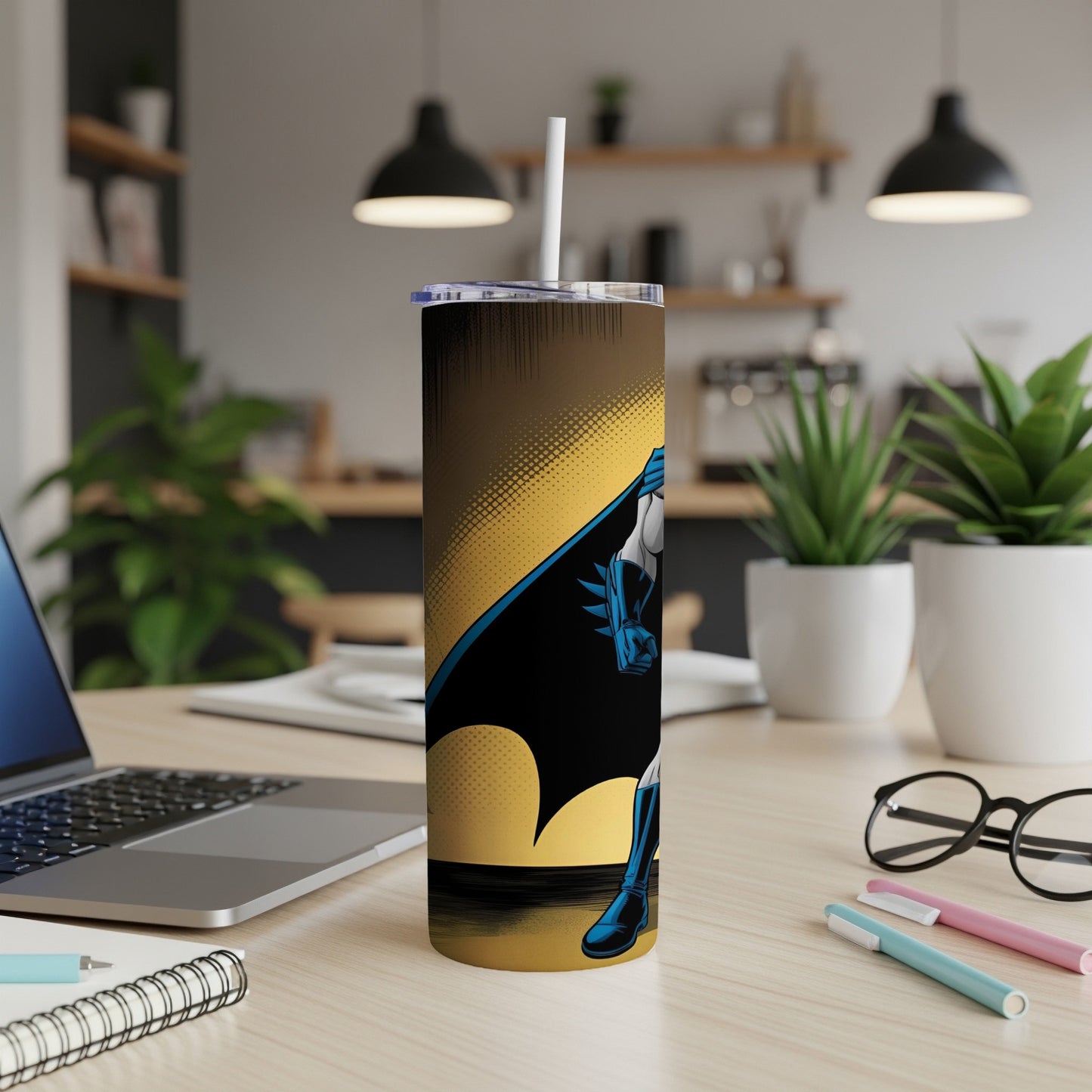 Batman graphic on a tall, insulated tumbler with a straw, on a desk.