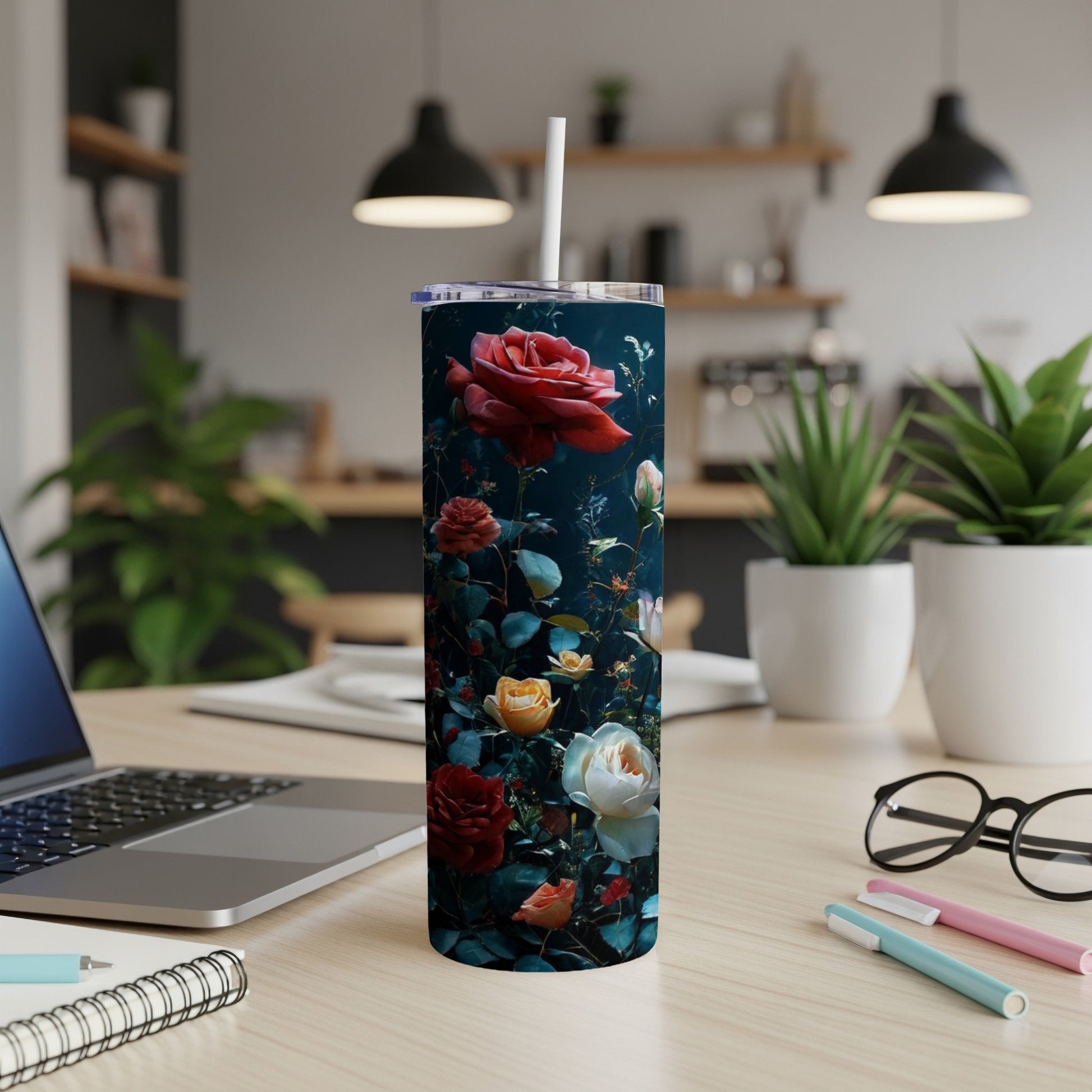 Floral tumbler with red, yellow, and white roses on a desk.