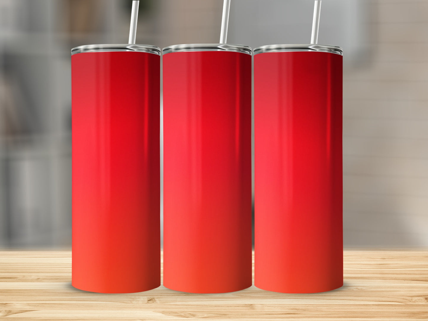Three red gradient tumblers with white straws on a wooden surface.