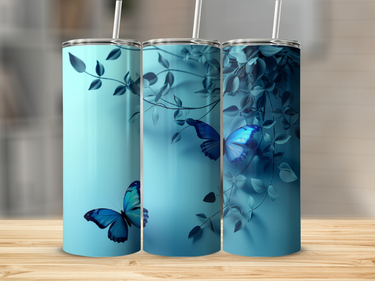 Blue butterfly and leaf design on three teal tumblers with straws.