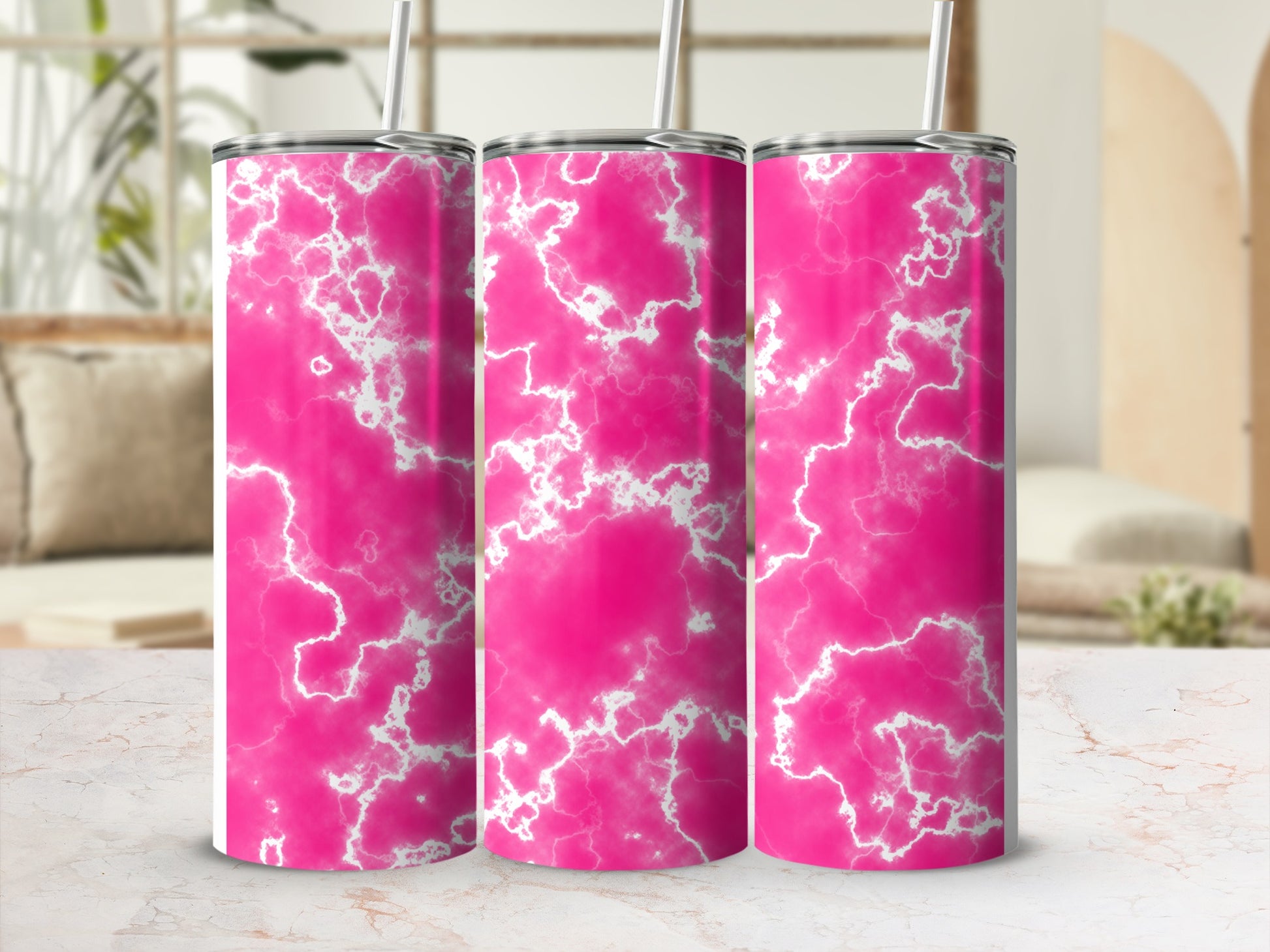 Three pink marbled tumblers with straws on a marbled surface.