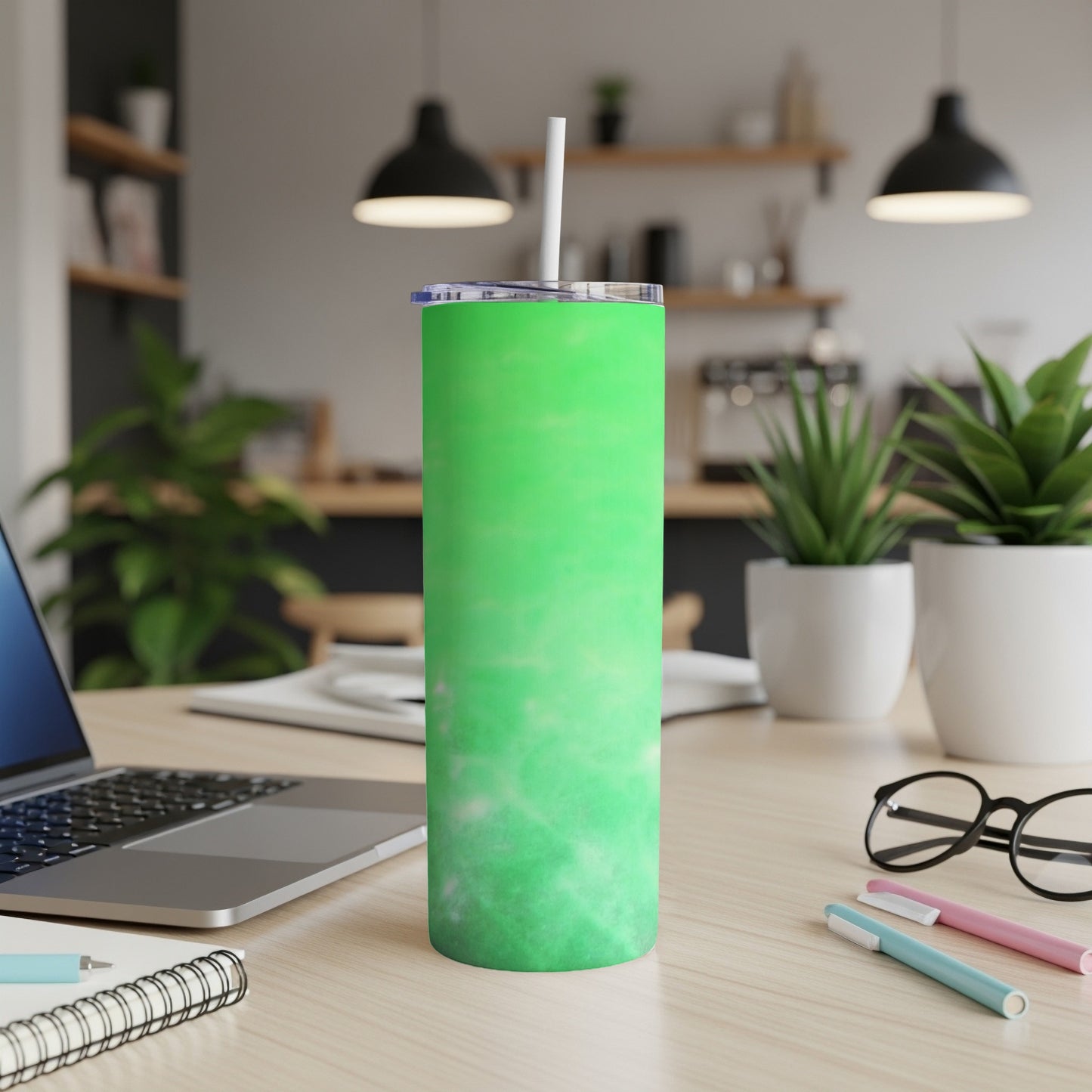 Green marbled tumbler with straw on a wooden desk.