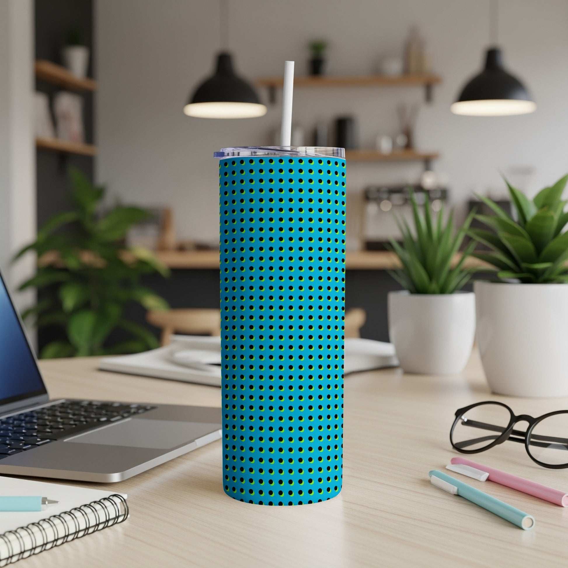 Blue tumbler with a dotted pattern and a straw on a wooden desk.