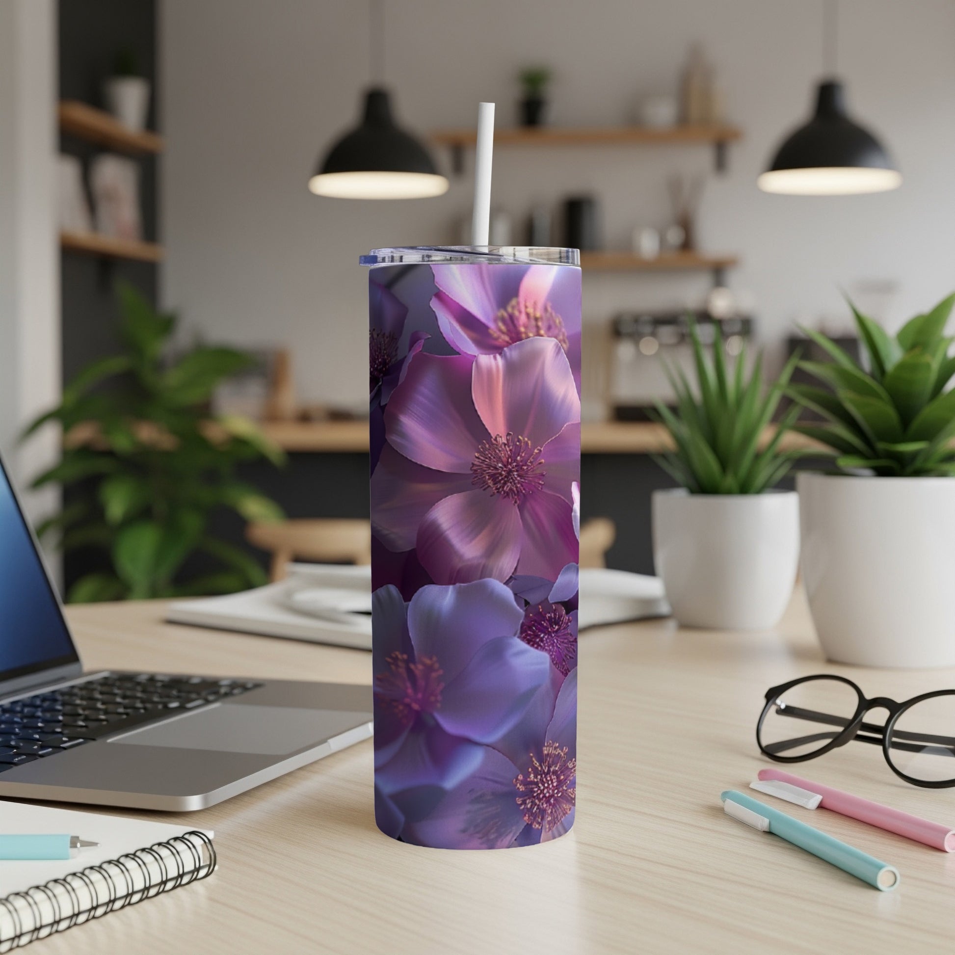 Purple floral tumbler with straw on desk next to laptop.